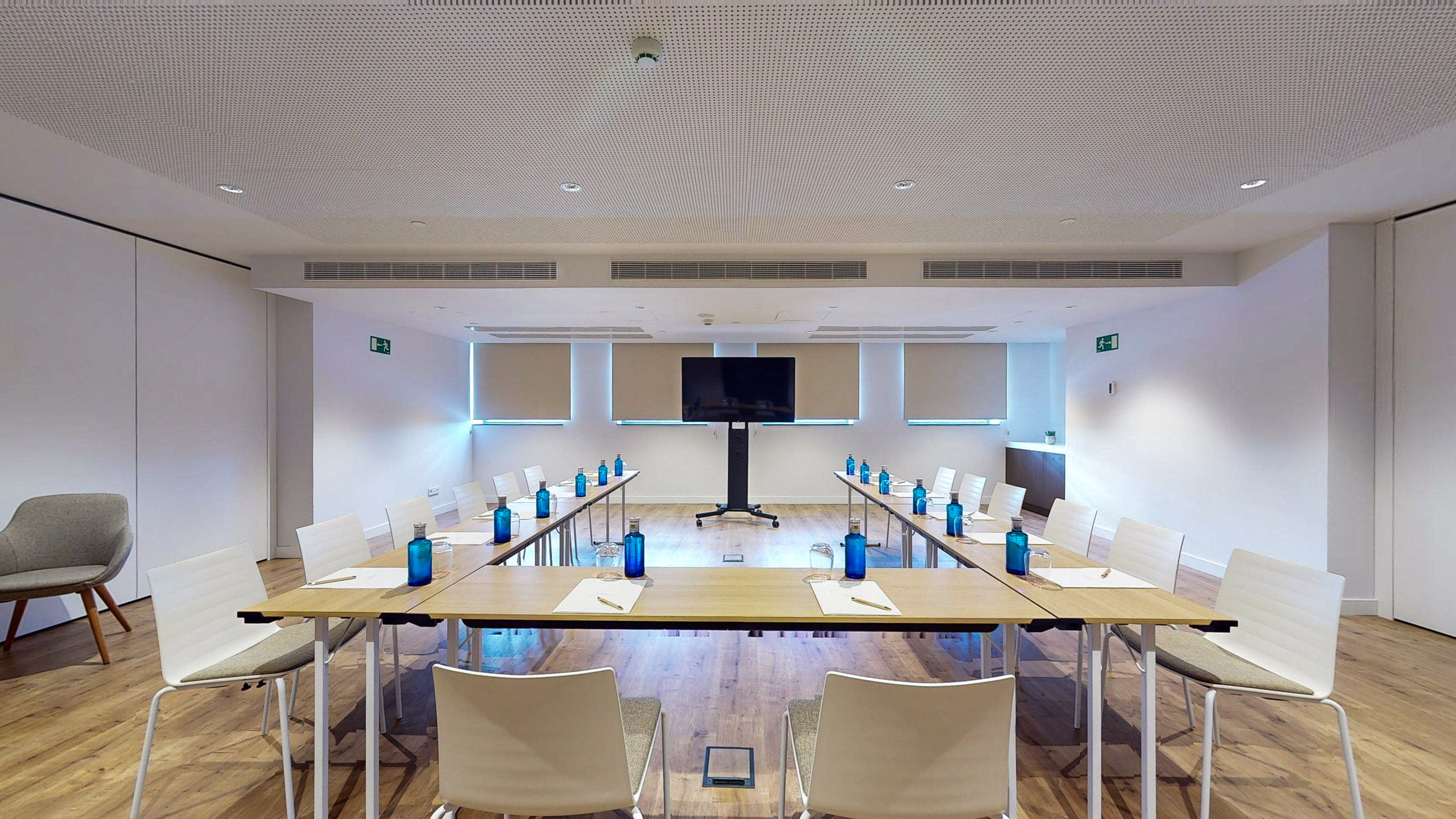 Modern conference room with U-shaped table setup and large TV screen.