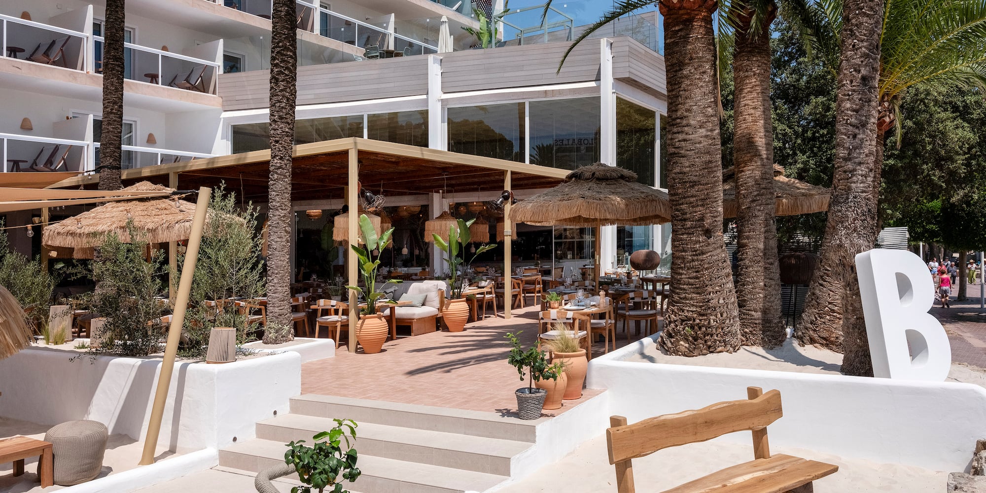a building with palm trees and a wooden bench