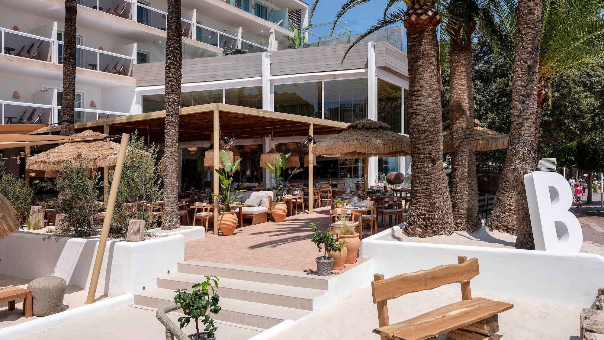 a building with palm trees and a wooden bench