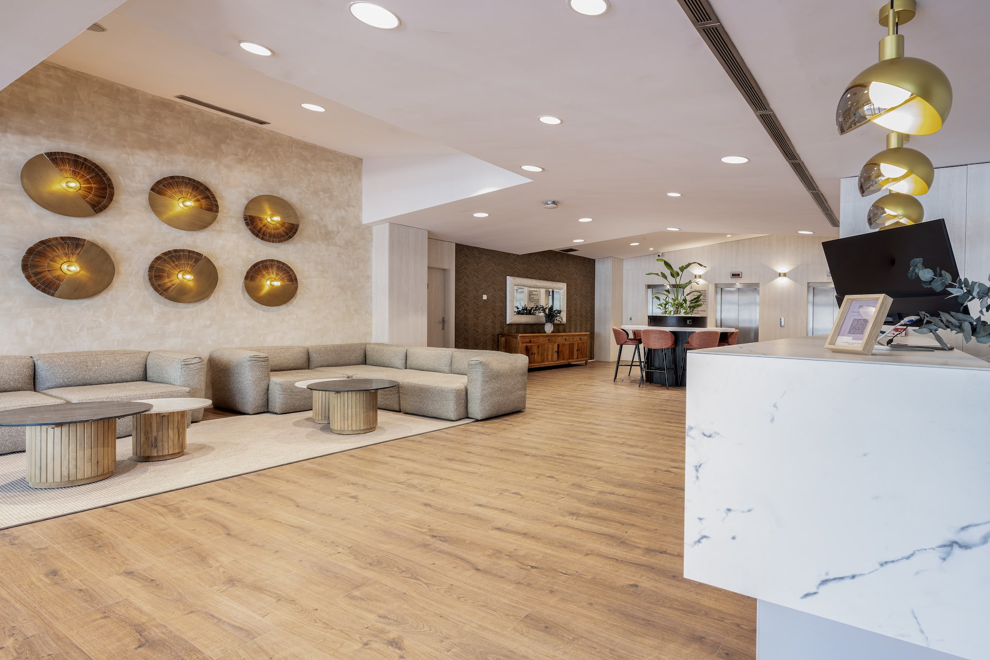 Modern hotel lobby with sleek lounge seating, wood floors, and gold accent lighting.