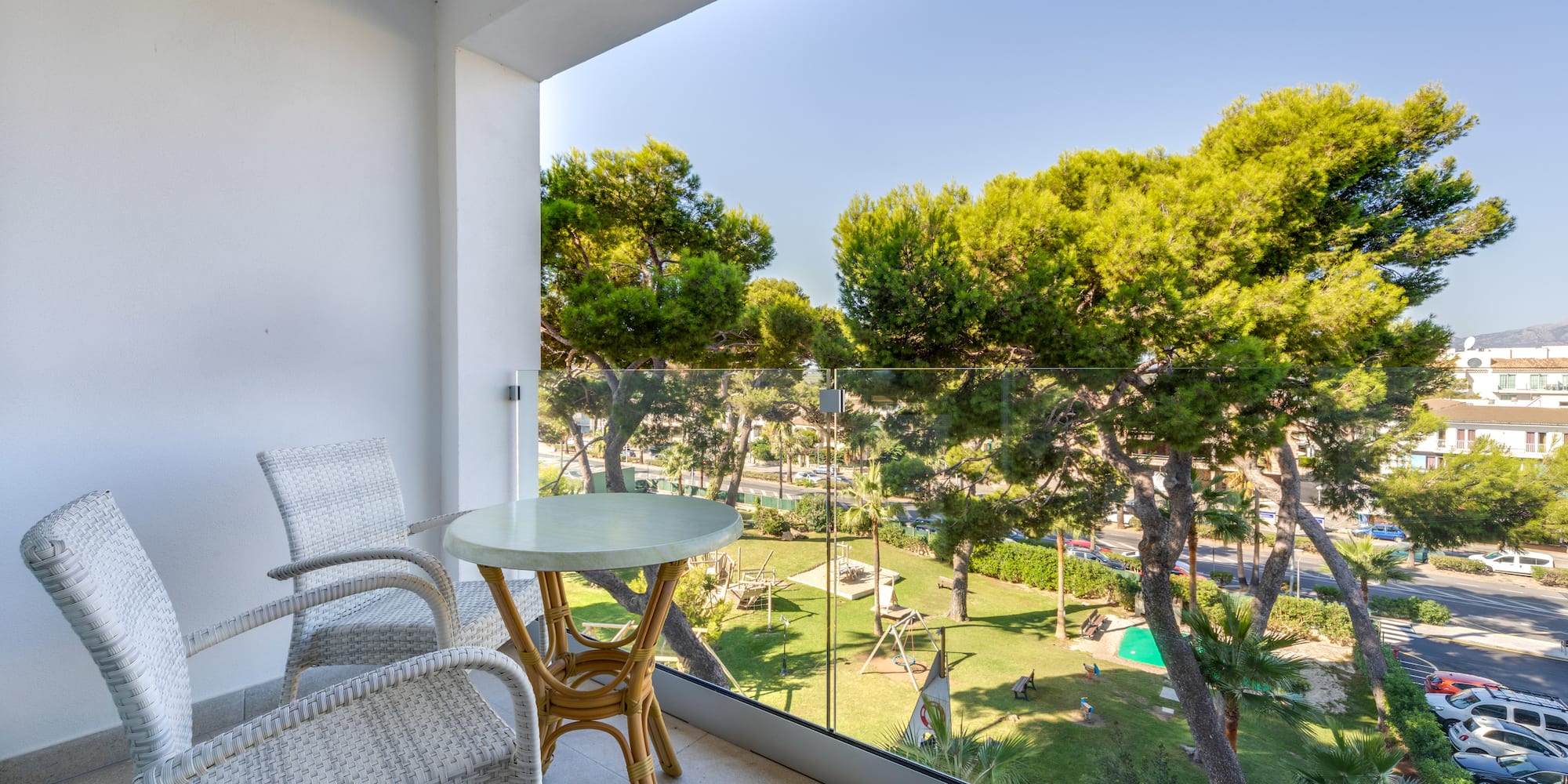 a table and chairs on a balcony overlooking trees and grass