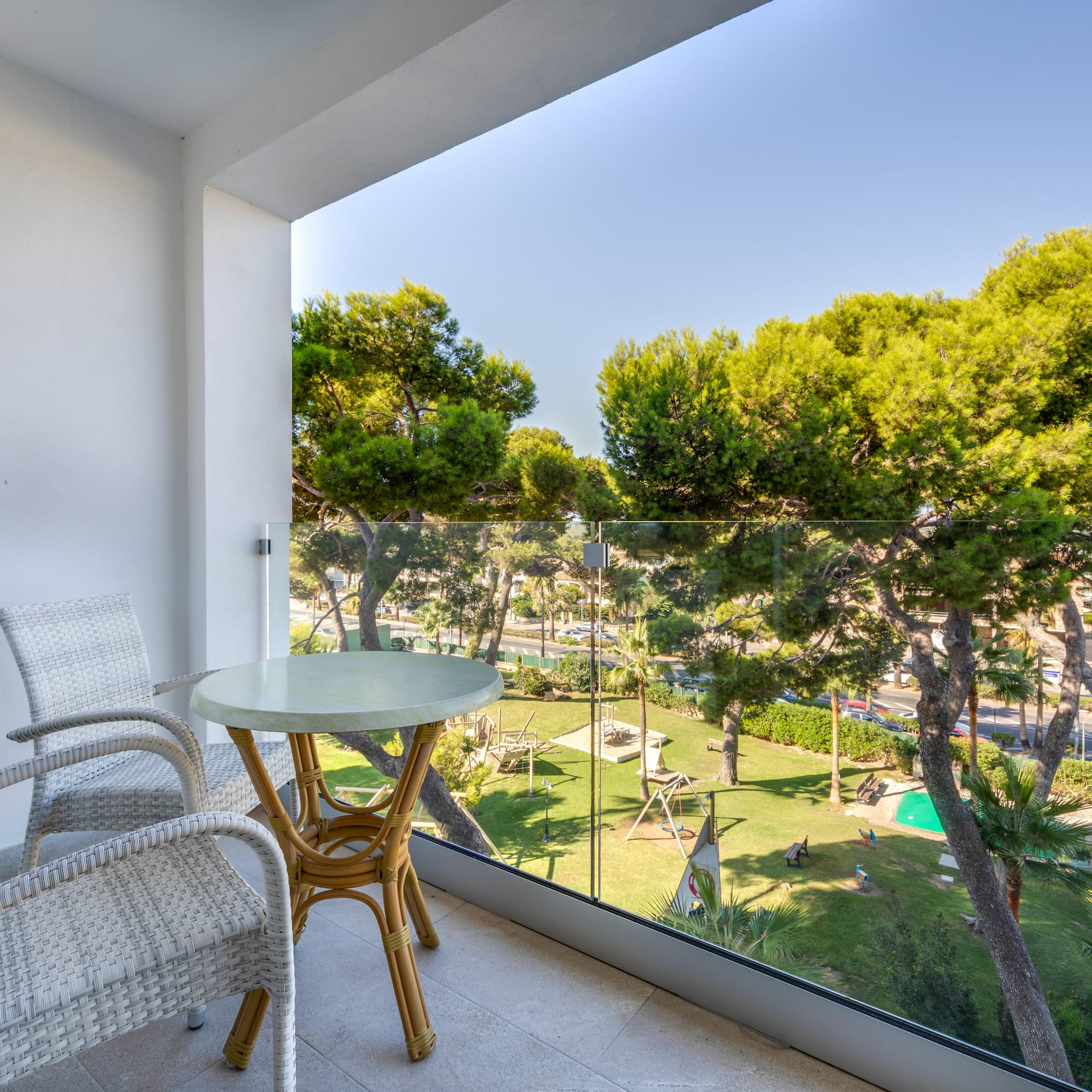 a table and chairs on a balcony overlooking trees and grass