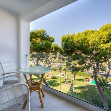 a table and chairs on a balcony overlooking trees and grass