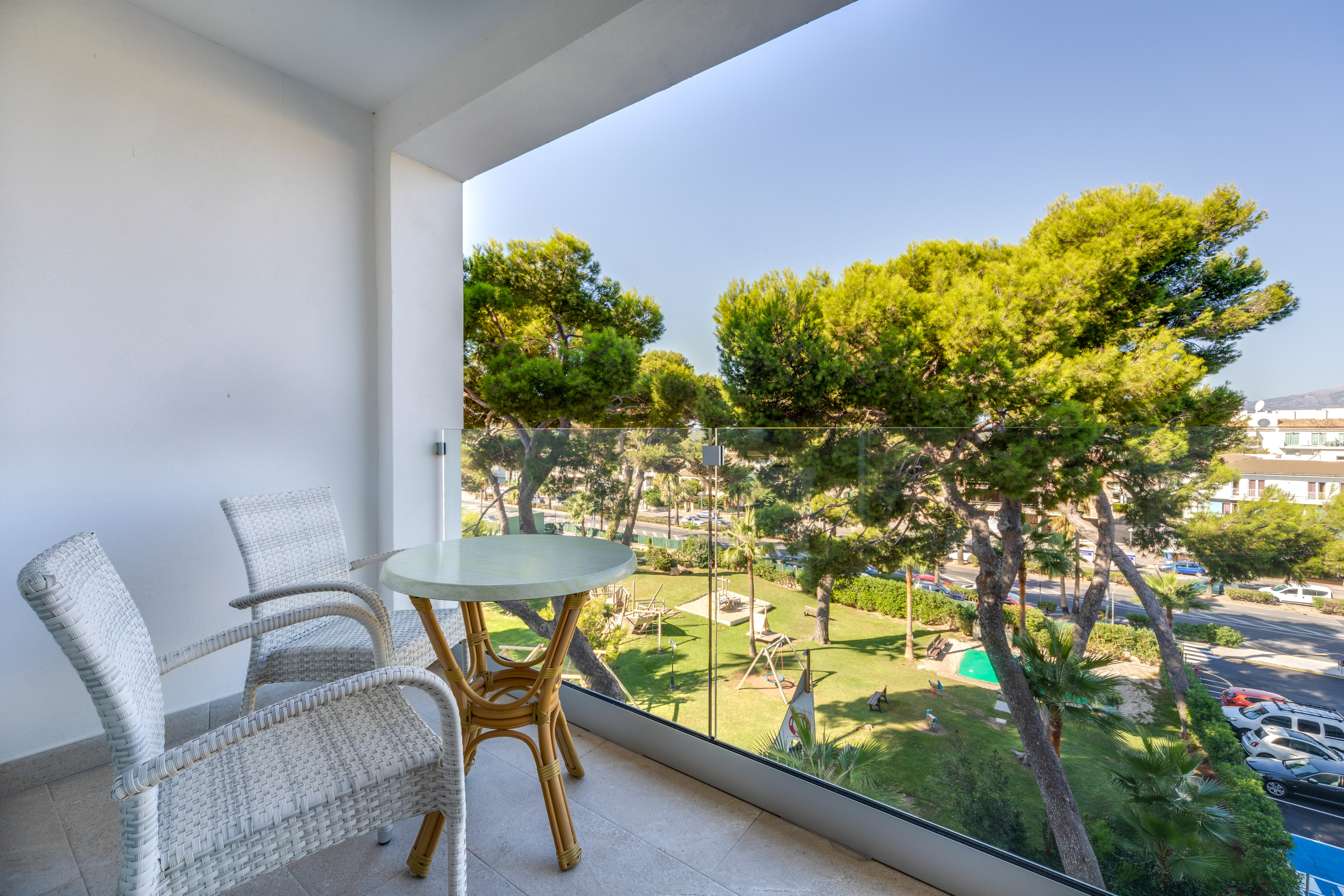 a table and chairs on a balcony overlooking trees and grass