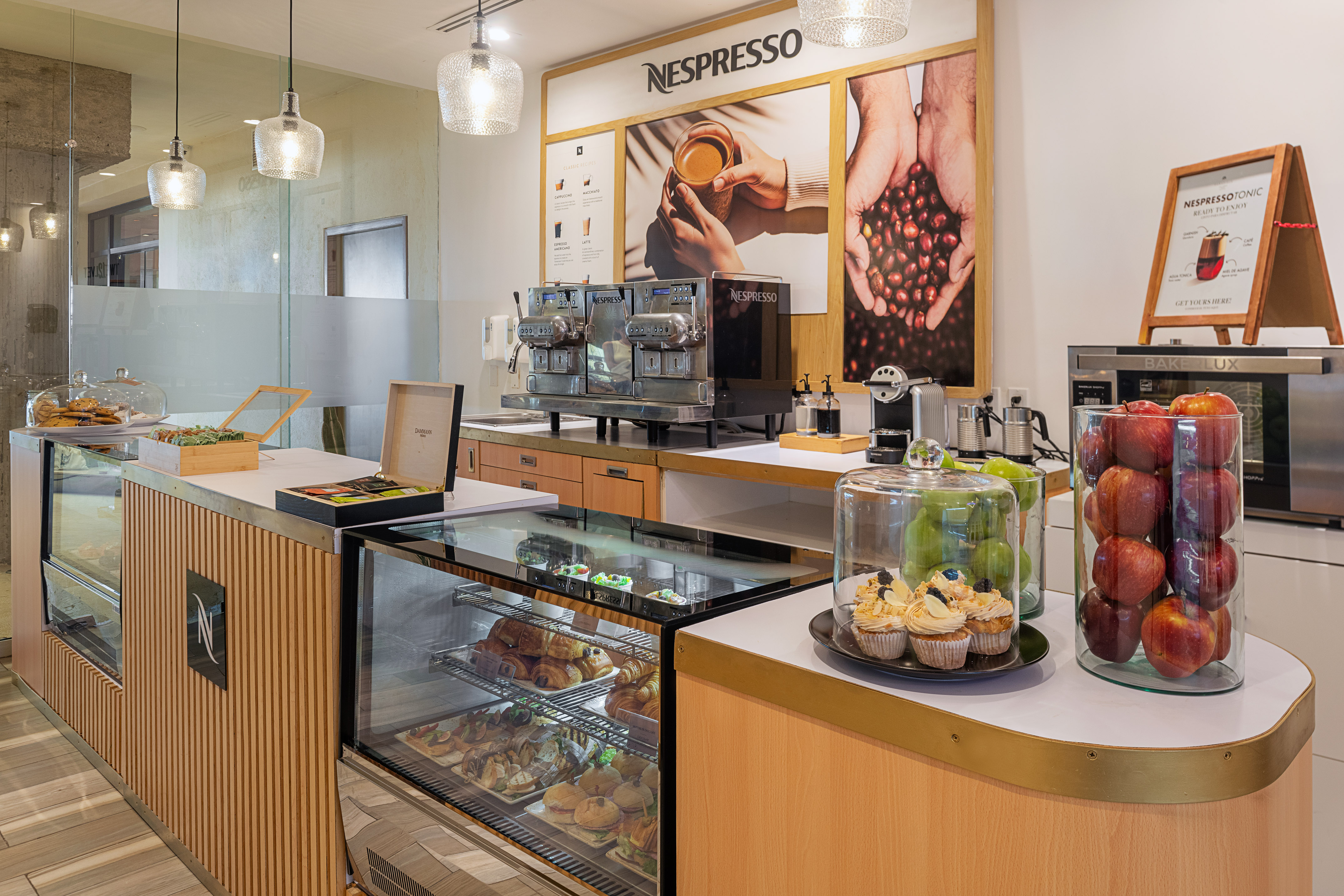 Modern Nespresso coffee bar with pastries, sandwiches, and fresh fruit display.