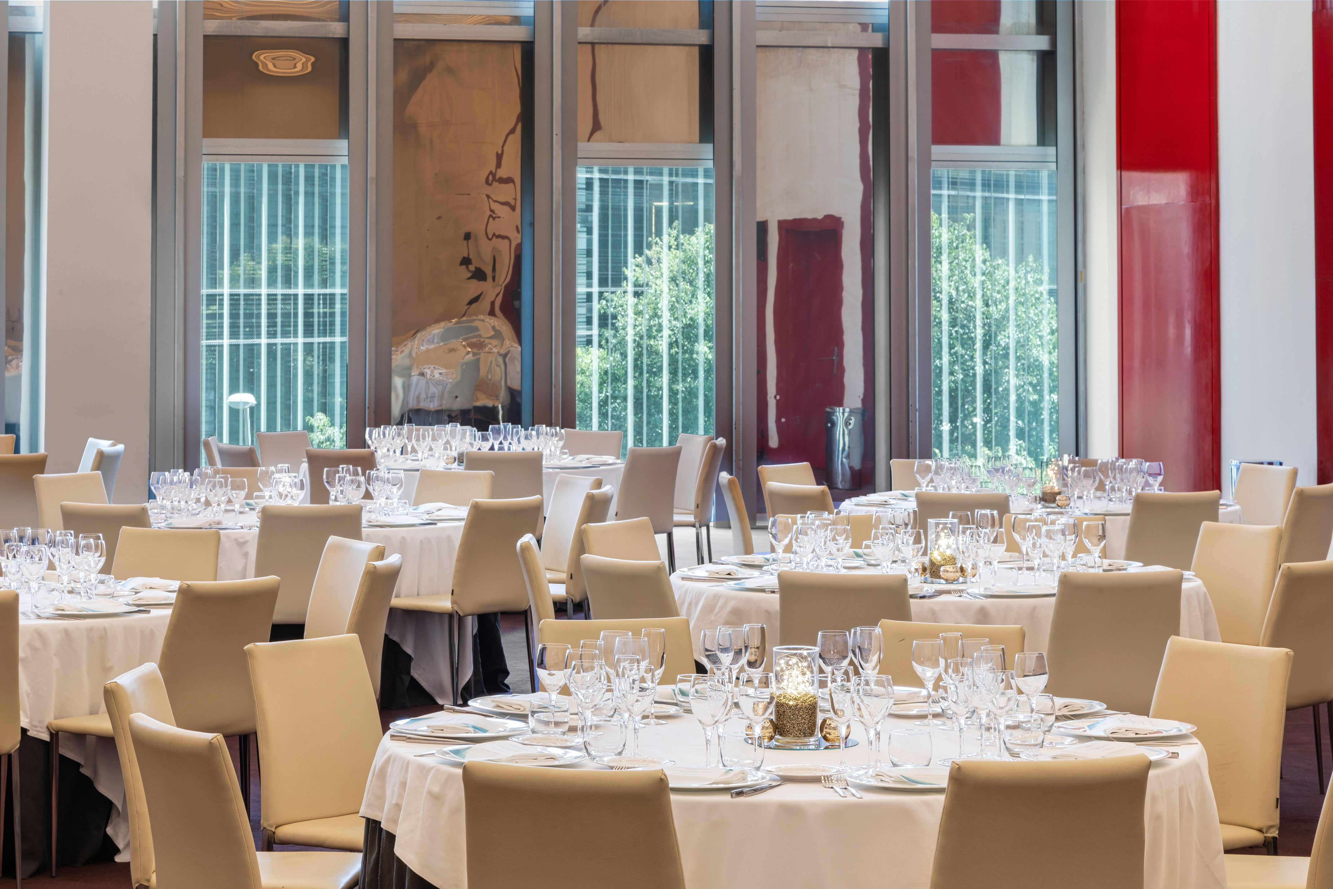 Modern banquet hall with round tables, white linens, and contemporary art.