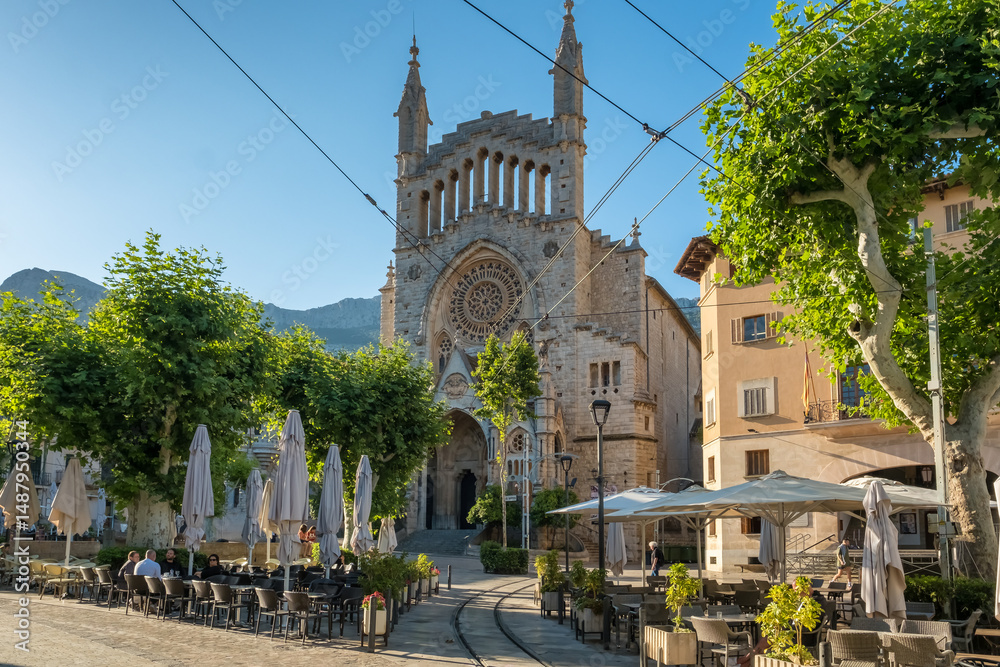 a building with a tower and a street with tables and chairs