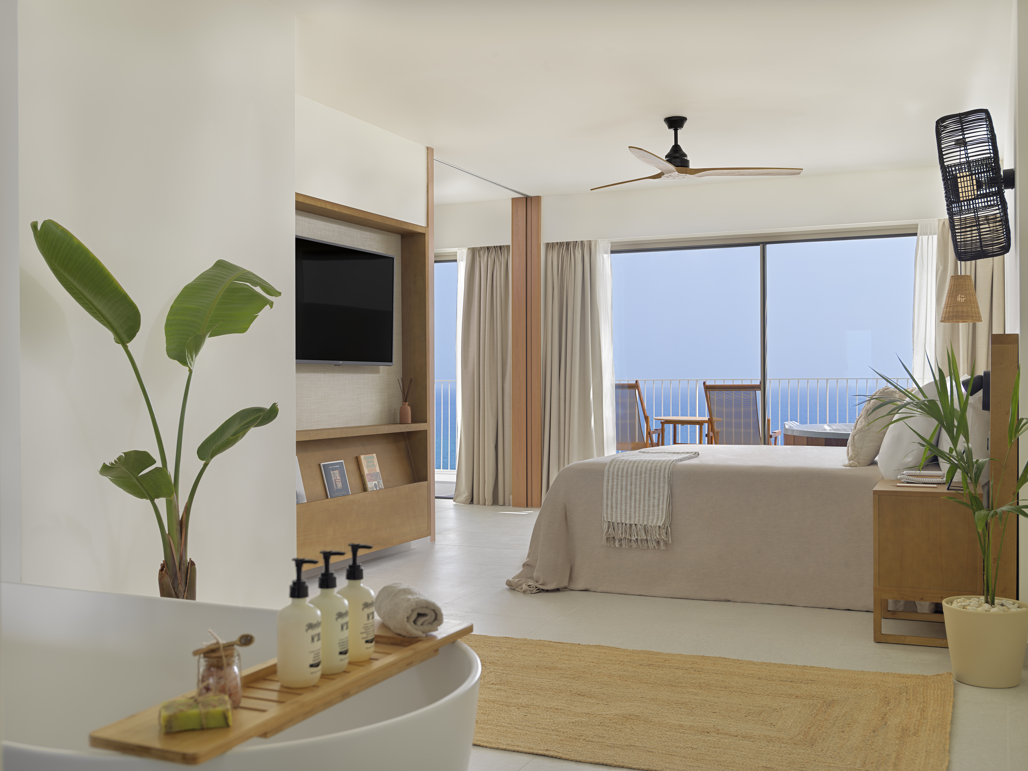 Luxury resort suite with ocean view balcony, modern bedroom, and bathtub.
