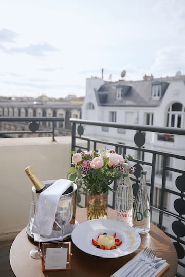 a table with a plate of champagne and flowers on a balcony