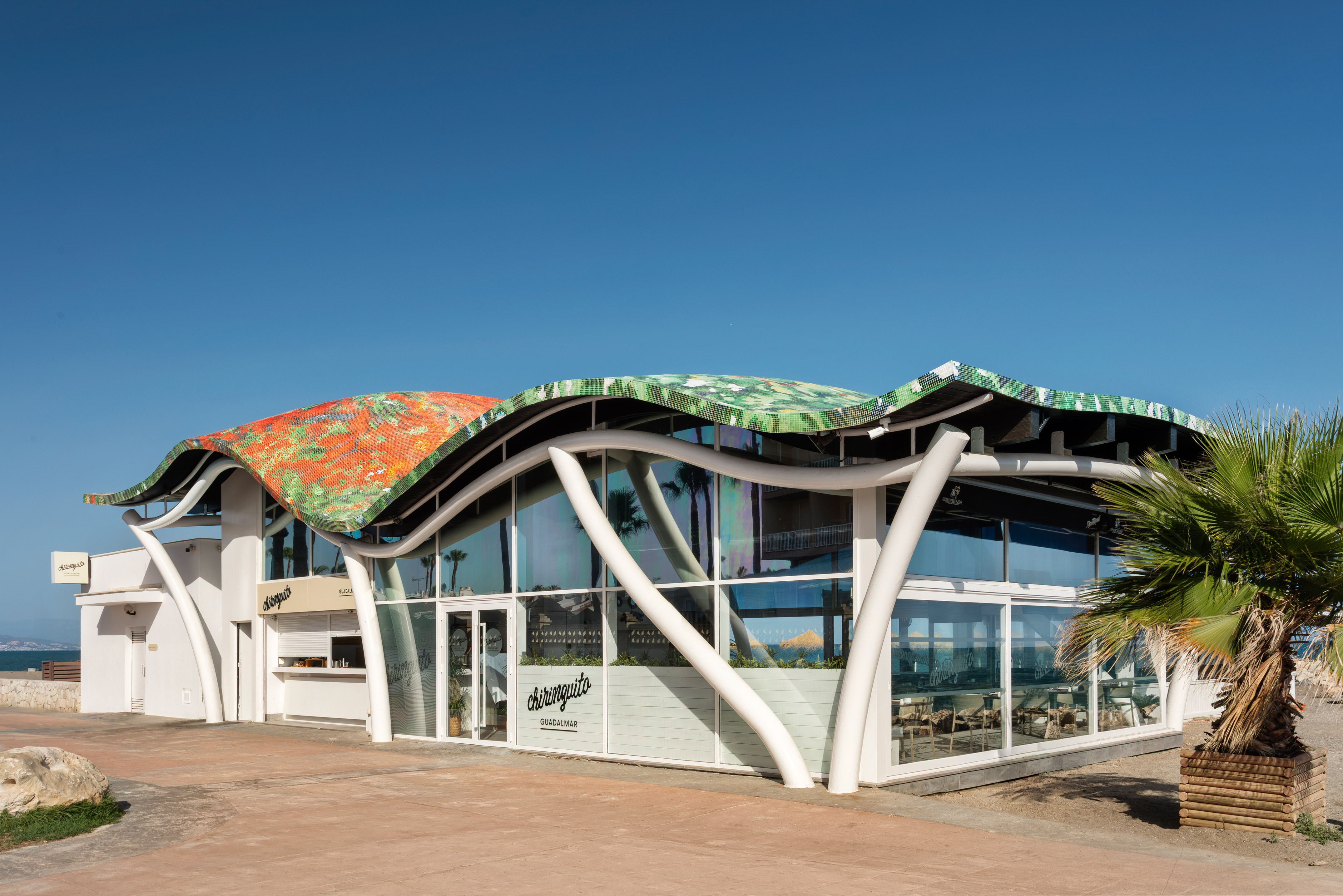 Chiringuito Guadalmar with colorful wavy roof, modern beachfront design.