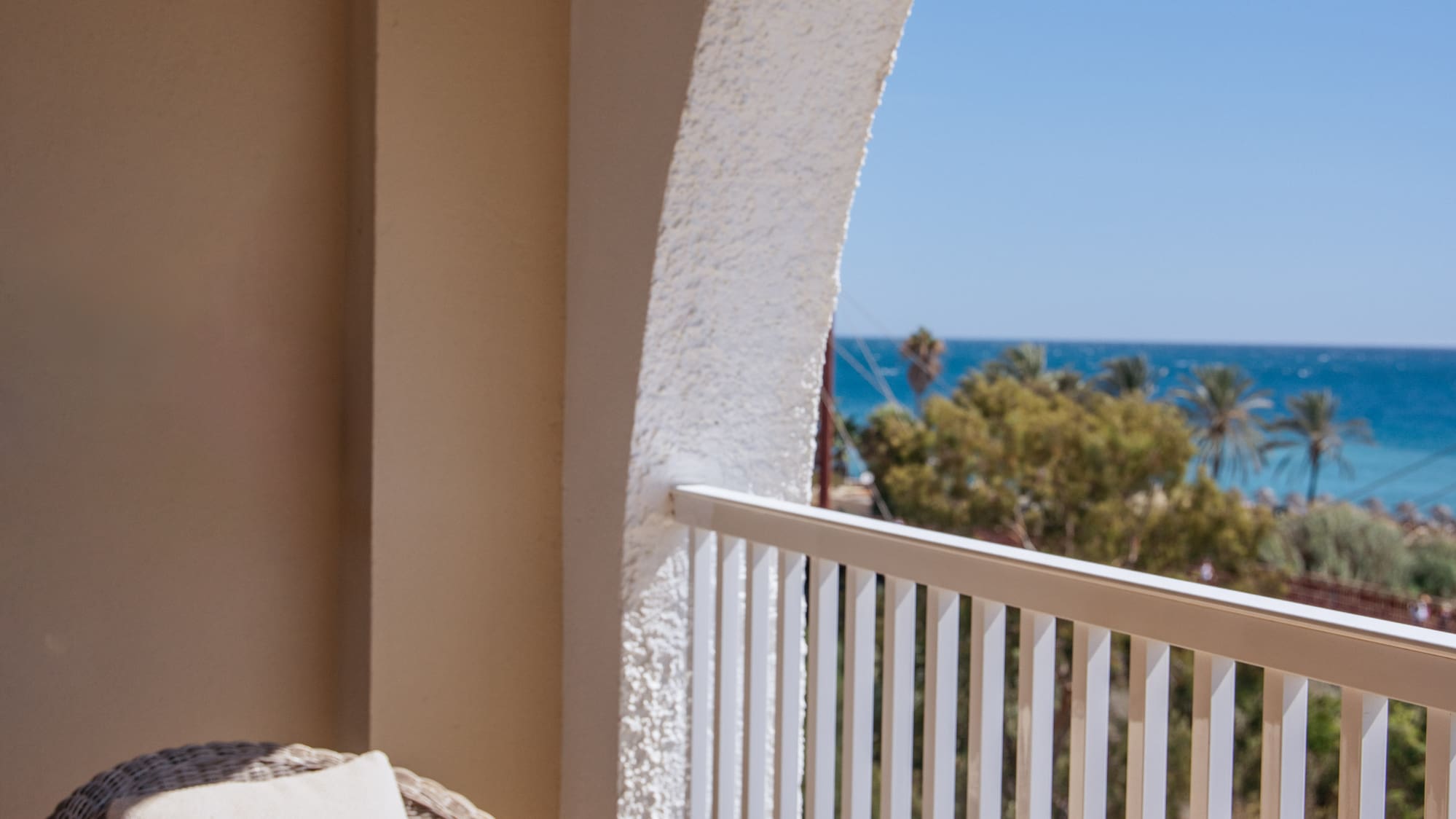 a table with glasses and a drink on a balcony overlooking the ocean