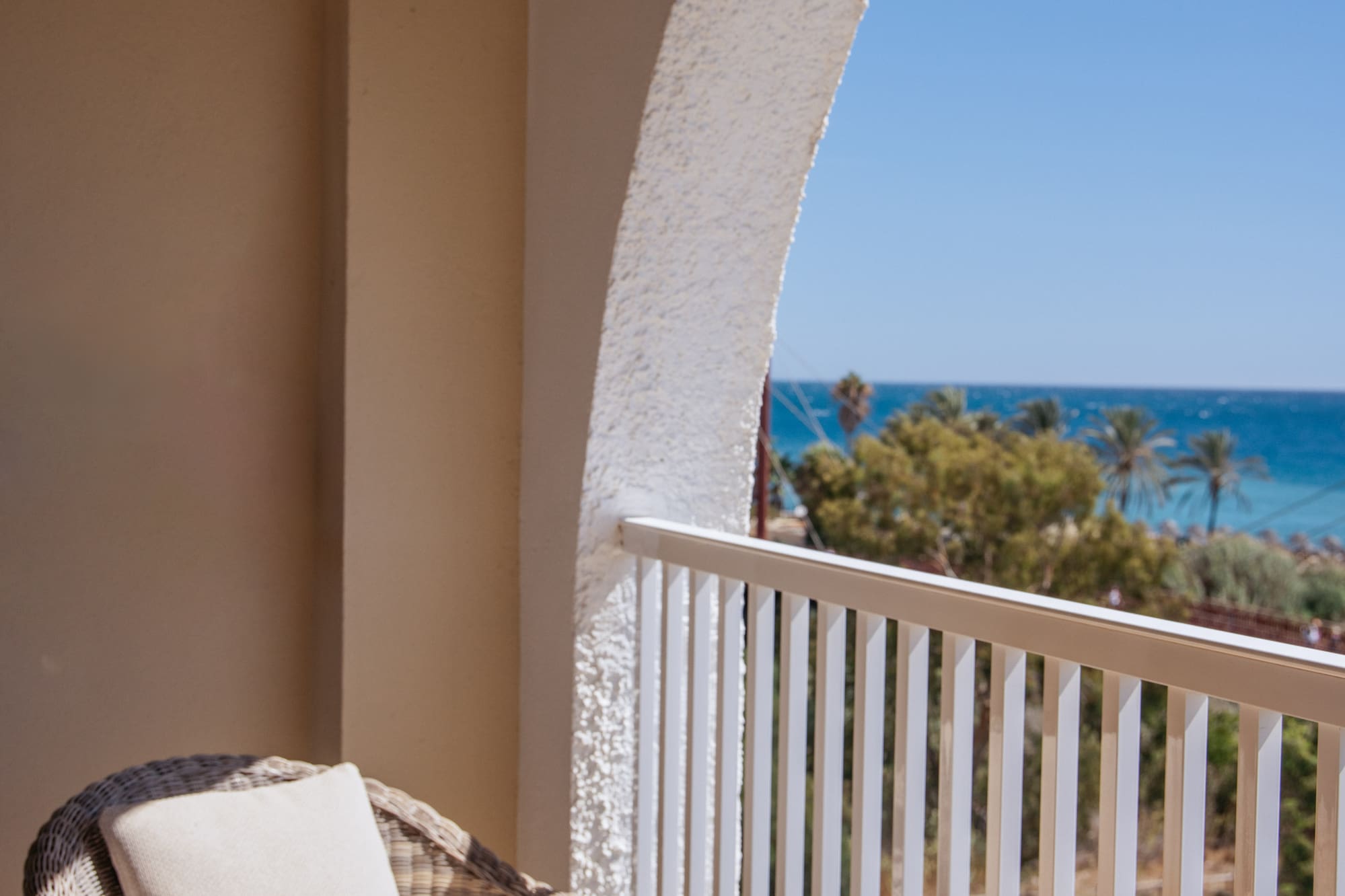 a table with glasses and a drink on a balcony overlooking the ocean