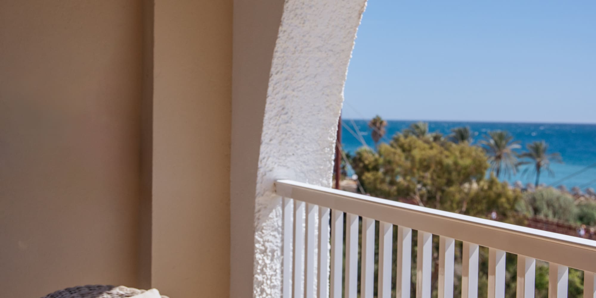 a table with glasses and a drink on a balcony overlooking the ocean