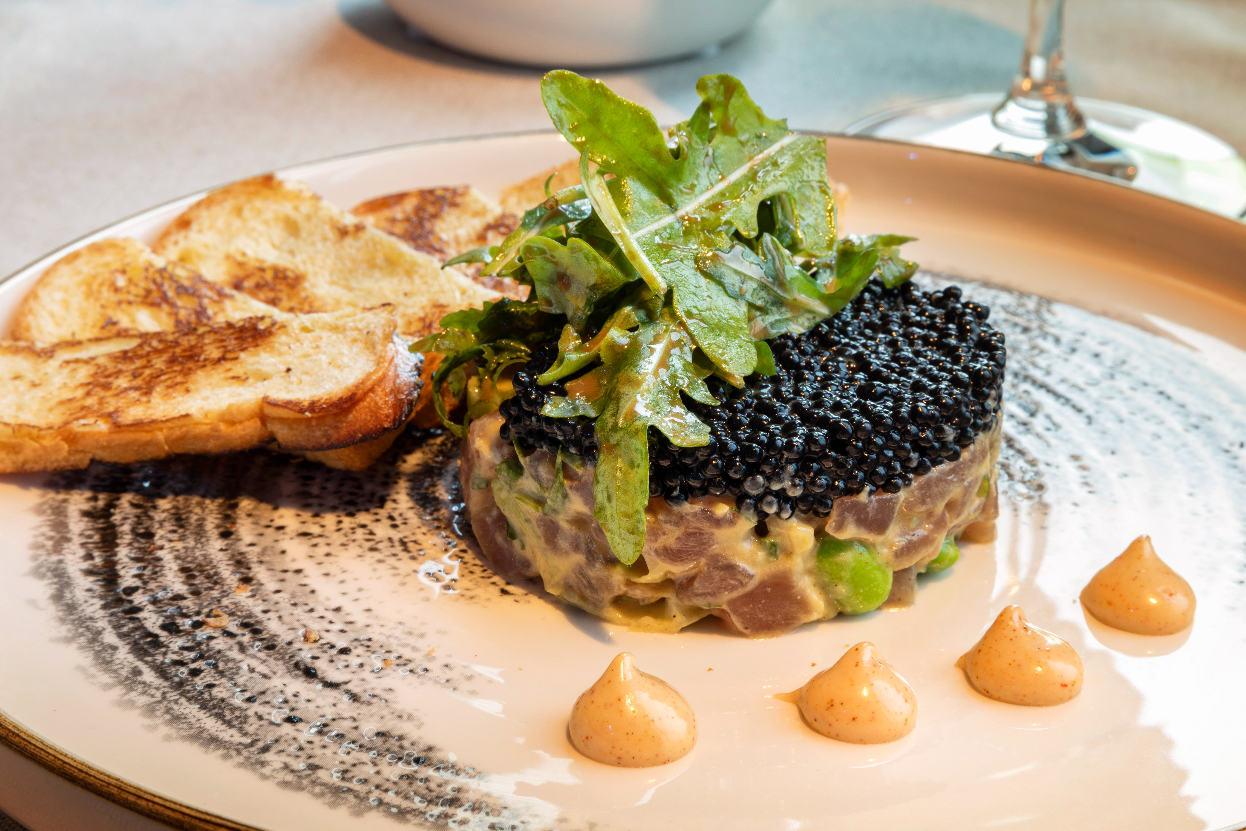 Tuna tartare with black caviar, fresh arugula, and golden toast.