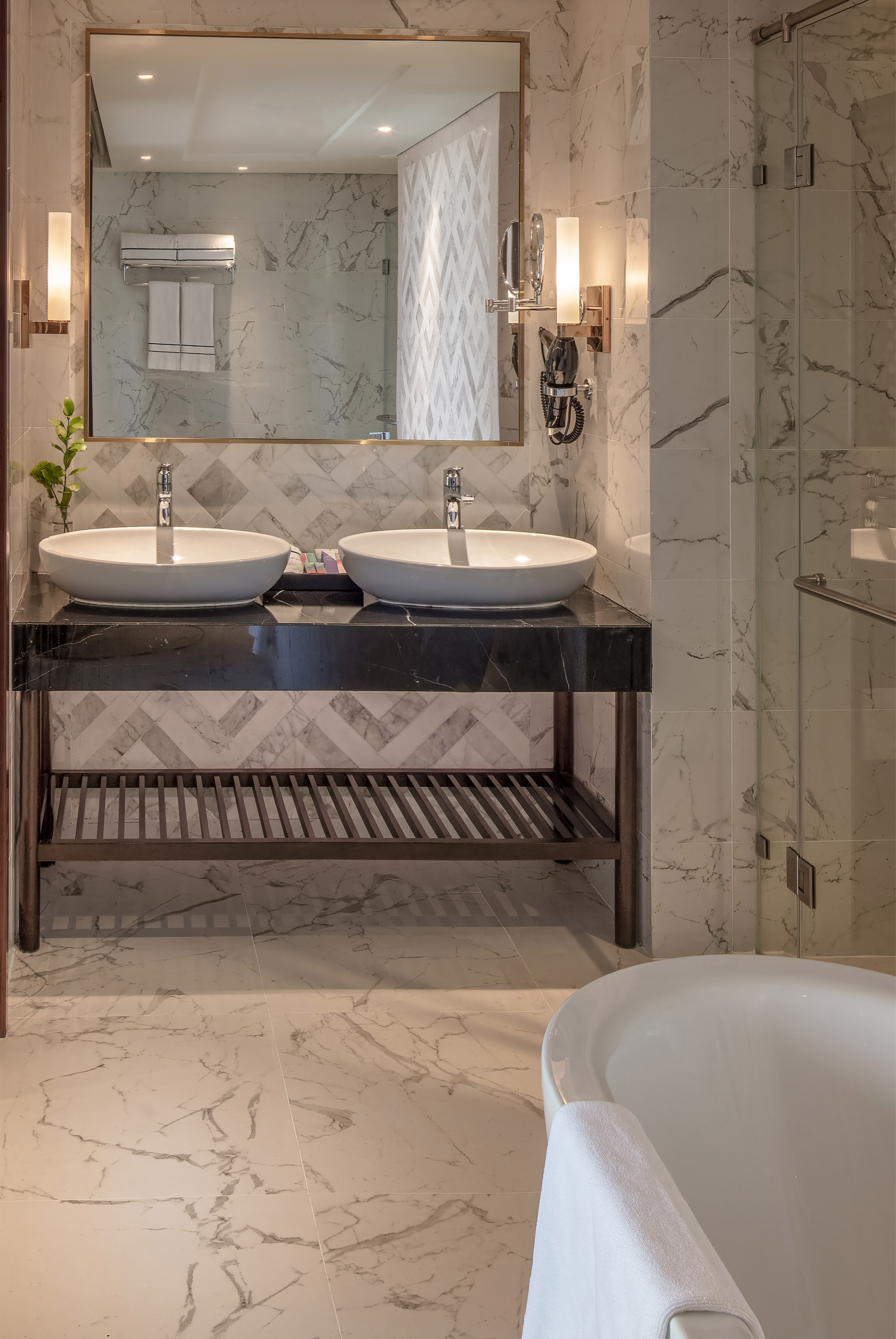Modern marble bathroom with double vanity, vessel sinks, and white freestanding tub.