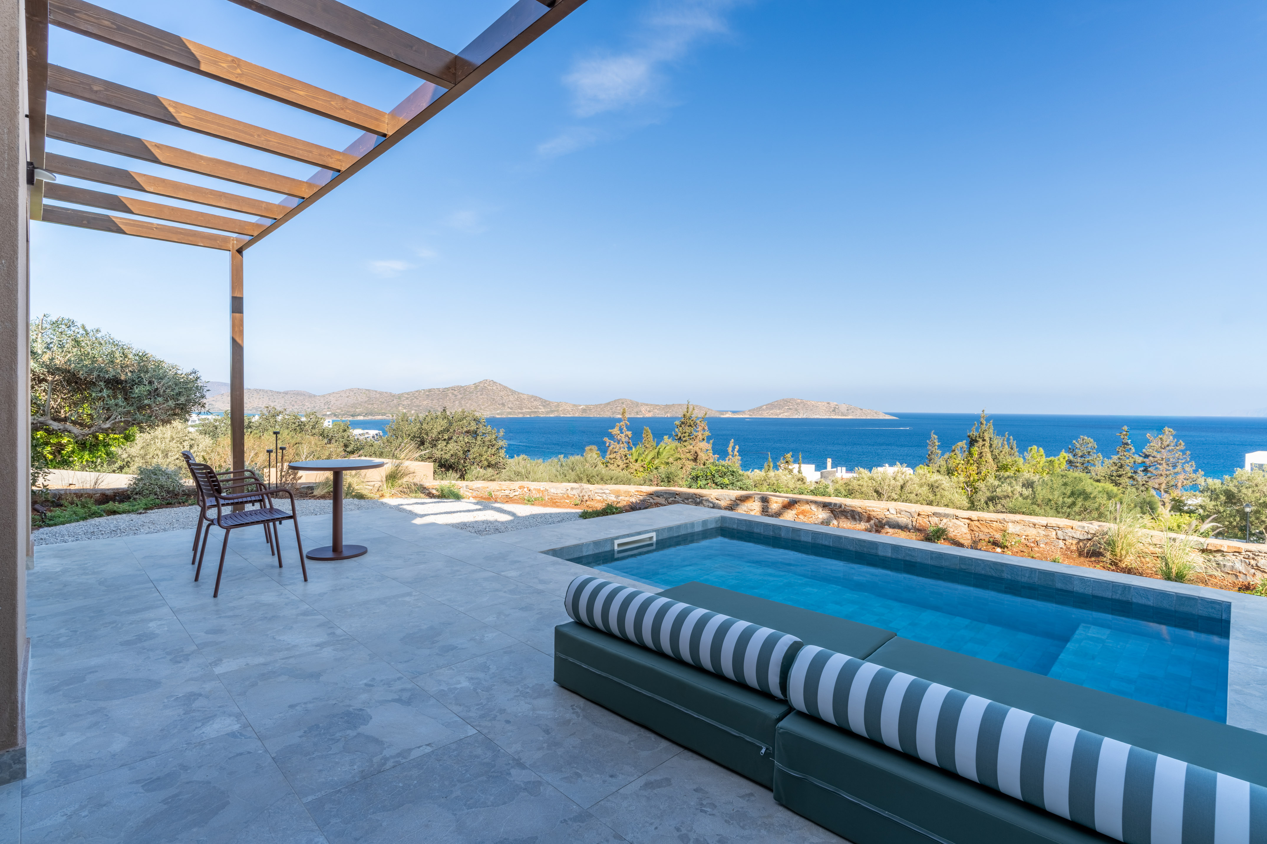Private plunge pool patio with ocean view, pergola, and daybed.