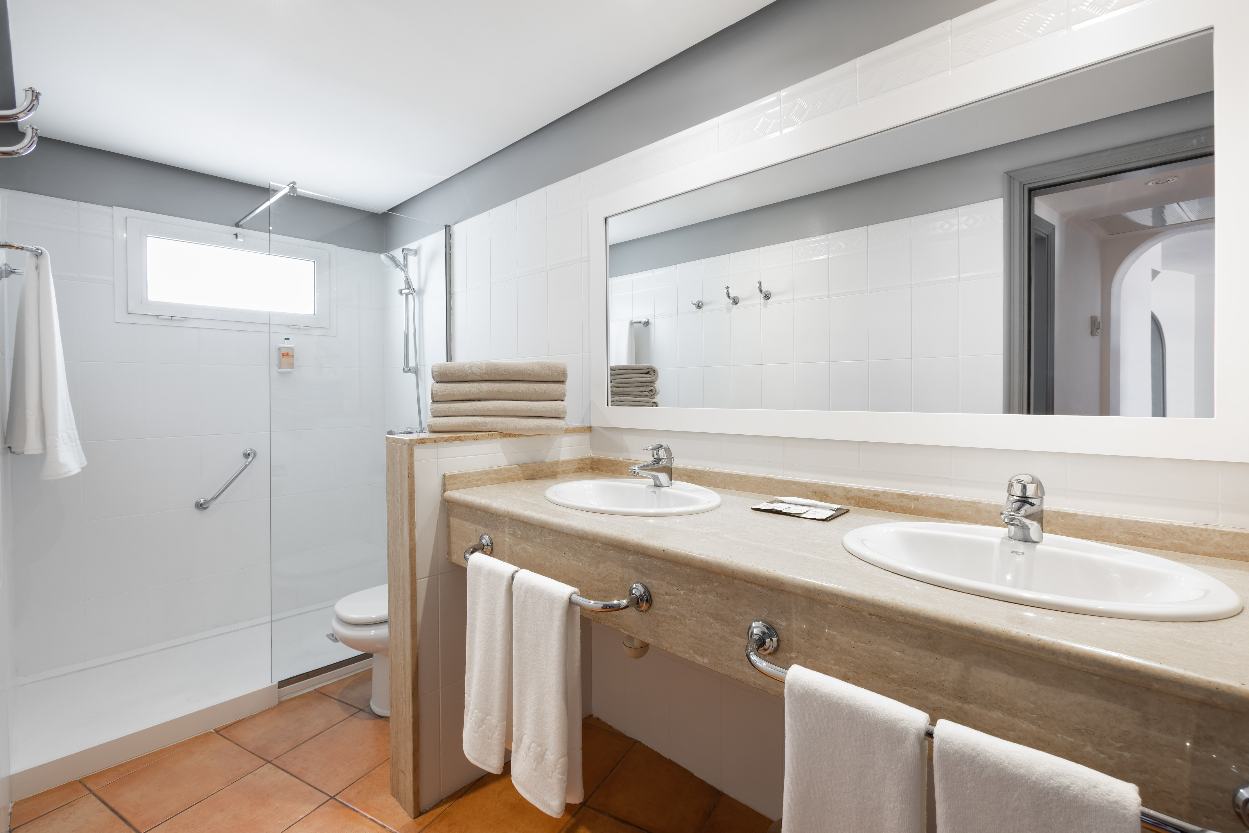 Spacious hotel bathroom with double vanity, large mirror, and walk-in shower.