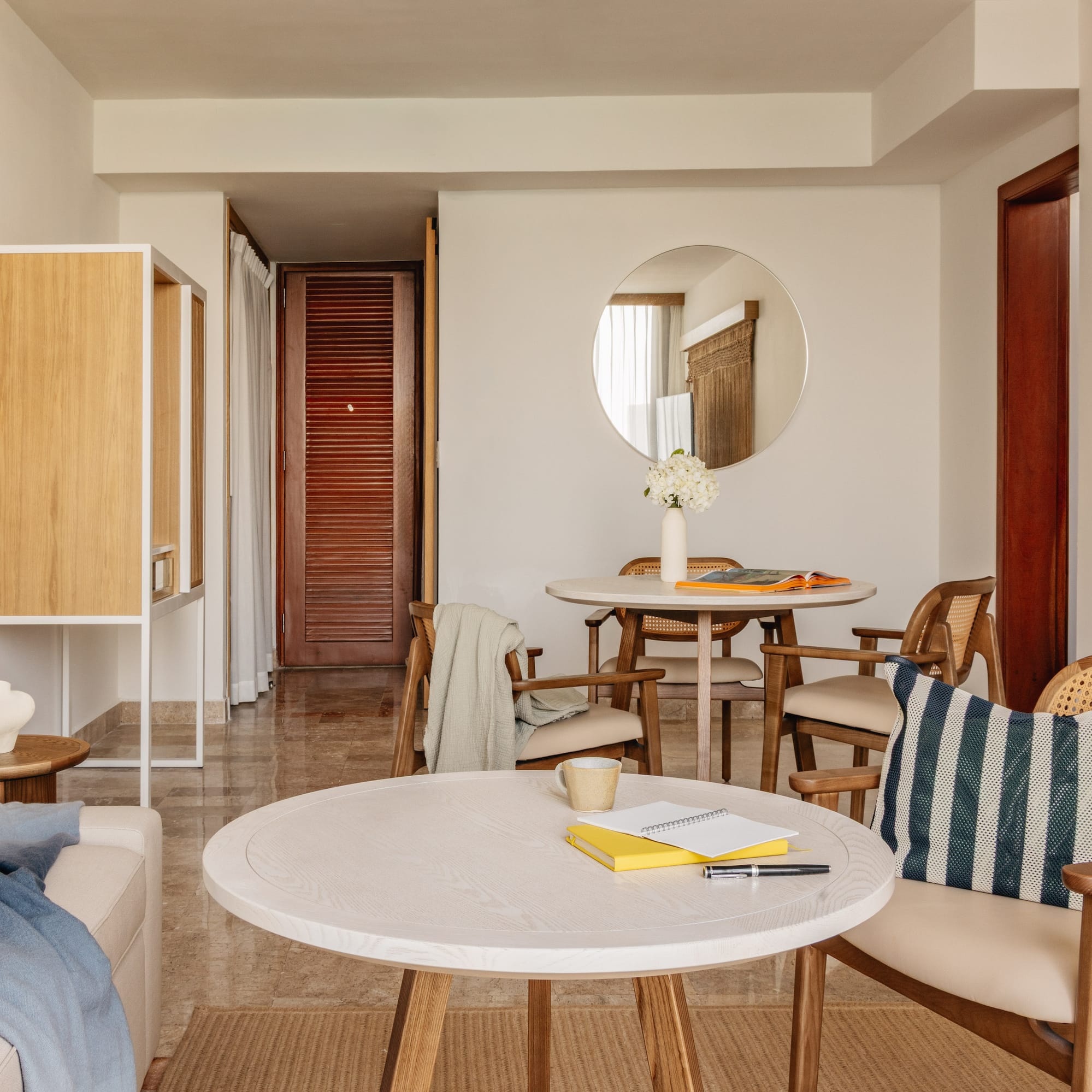 Modern living and dining room with rattan chairs, light wood tables, neutral decor.