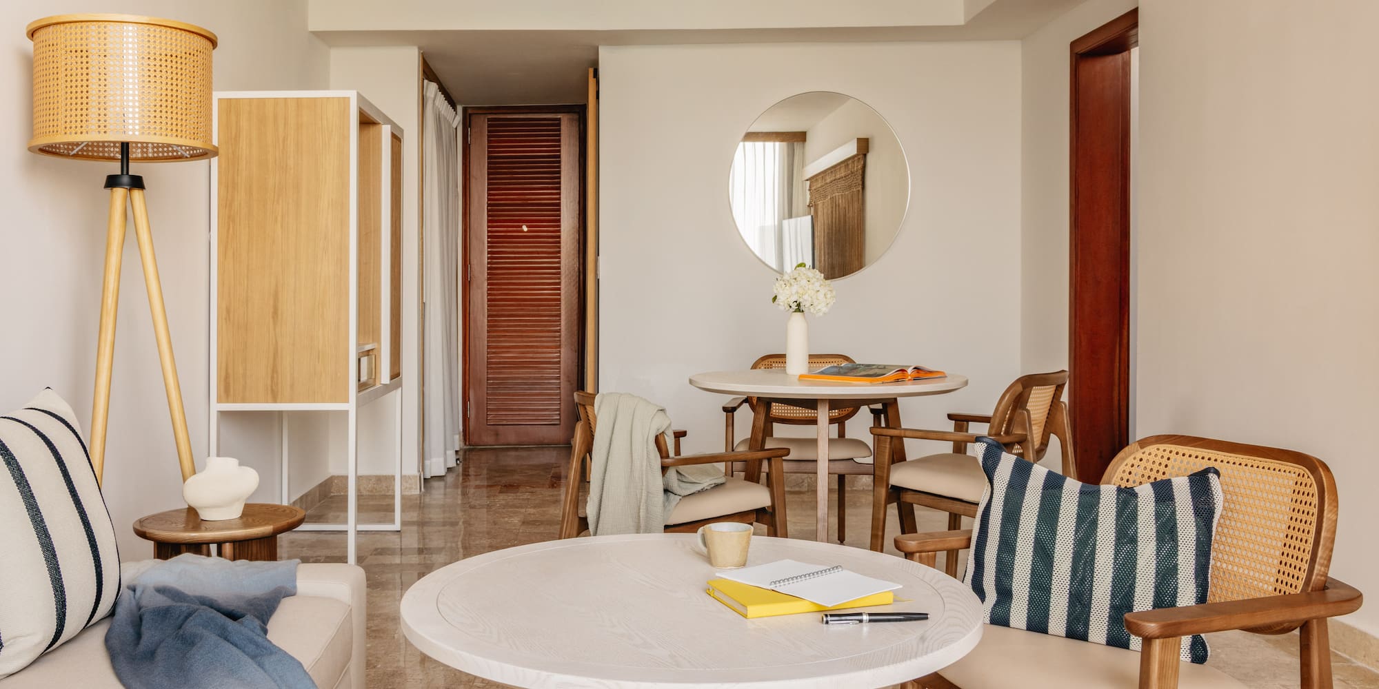 Modern living and dining room with rattan chairs, light wood tables, neutral decor.
