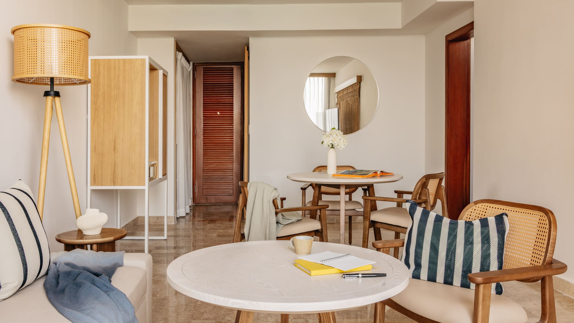Modern living and dining room with rattan chairs, light wood tables, neutral decor.