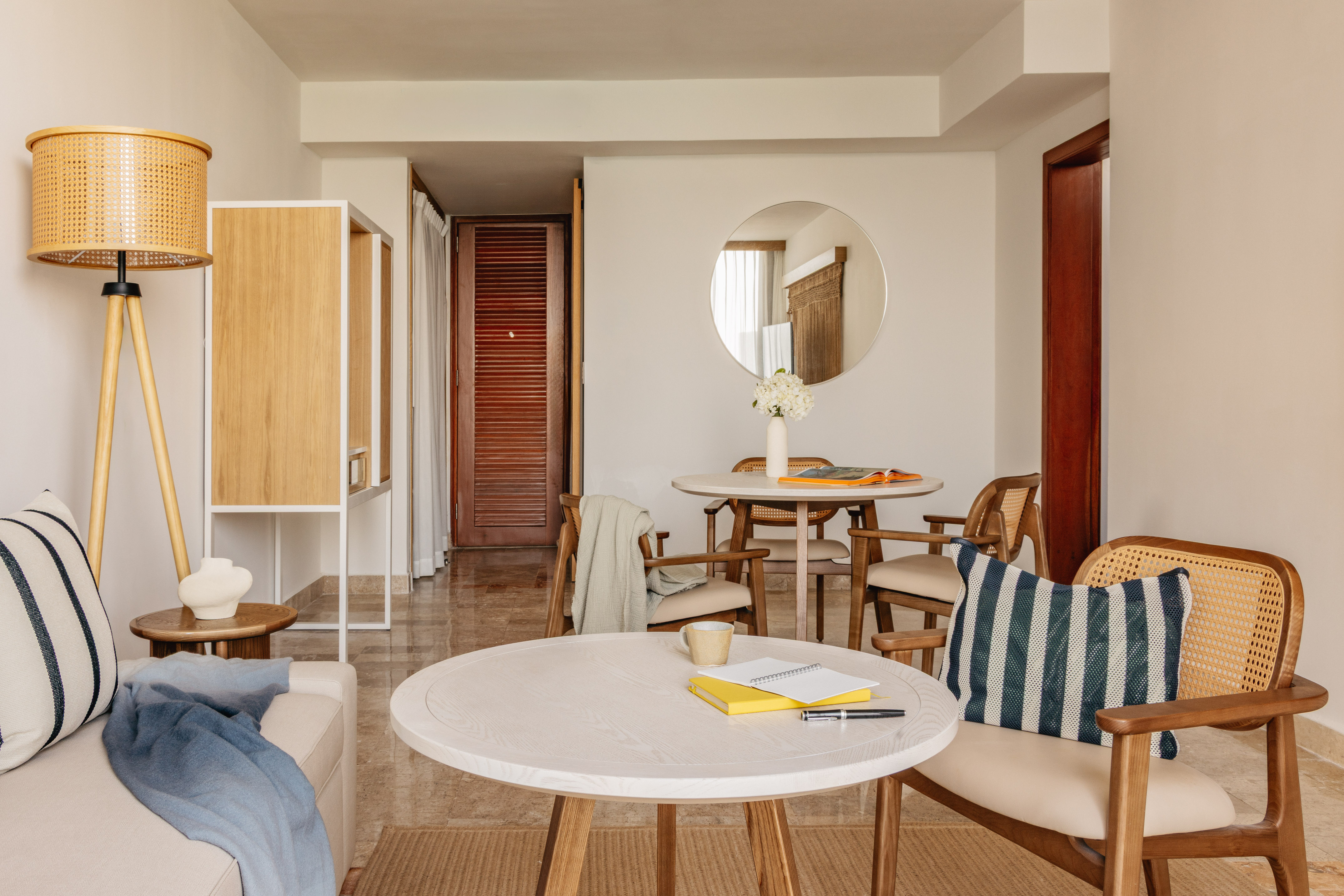 Modern living and dining room with rattan chairs, light wood tables, neutral decor.