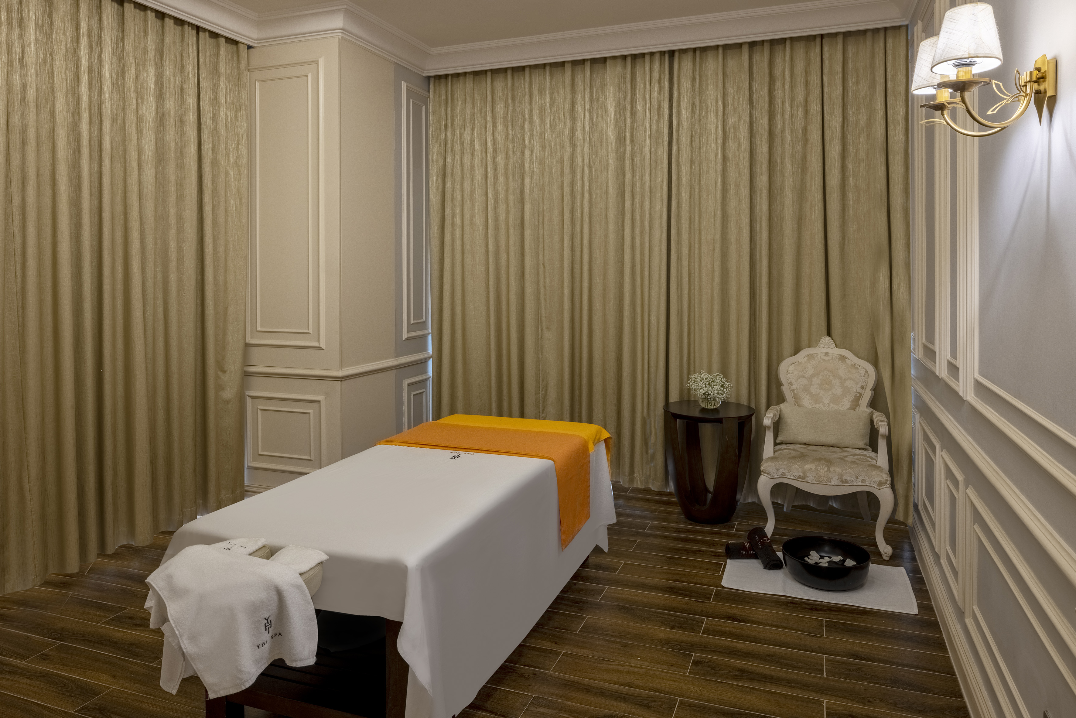 YHI Spa massage room with treatment table, ornate chair, foot bath.