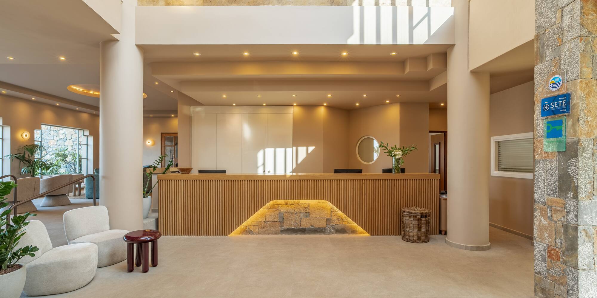 Modern hotel lobby with wood reception desk, natural light, and lounge seating.