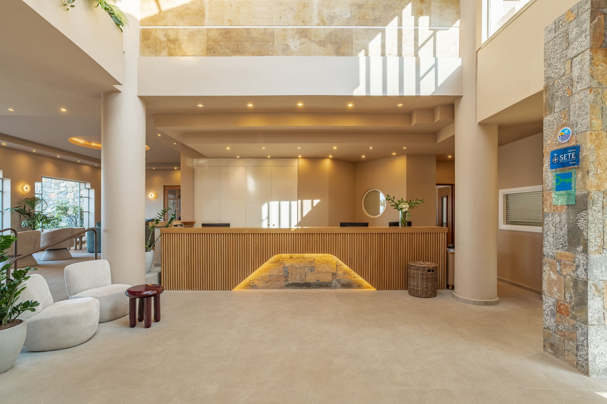 Modern hotel lobby with wood reception desk, natural light, and lounge seating.