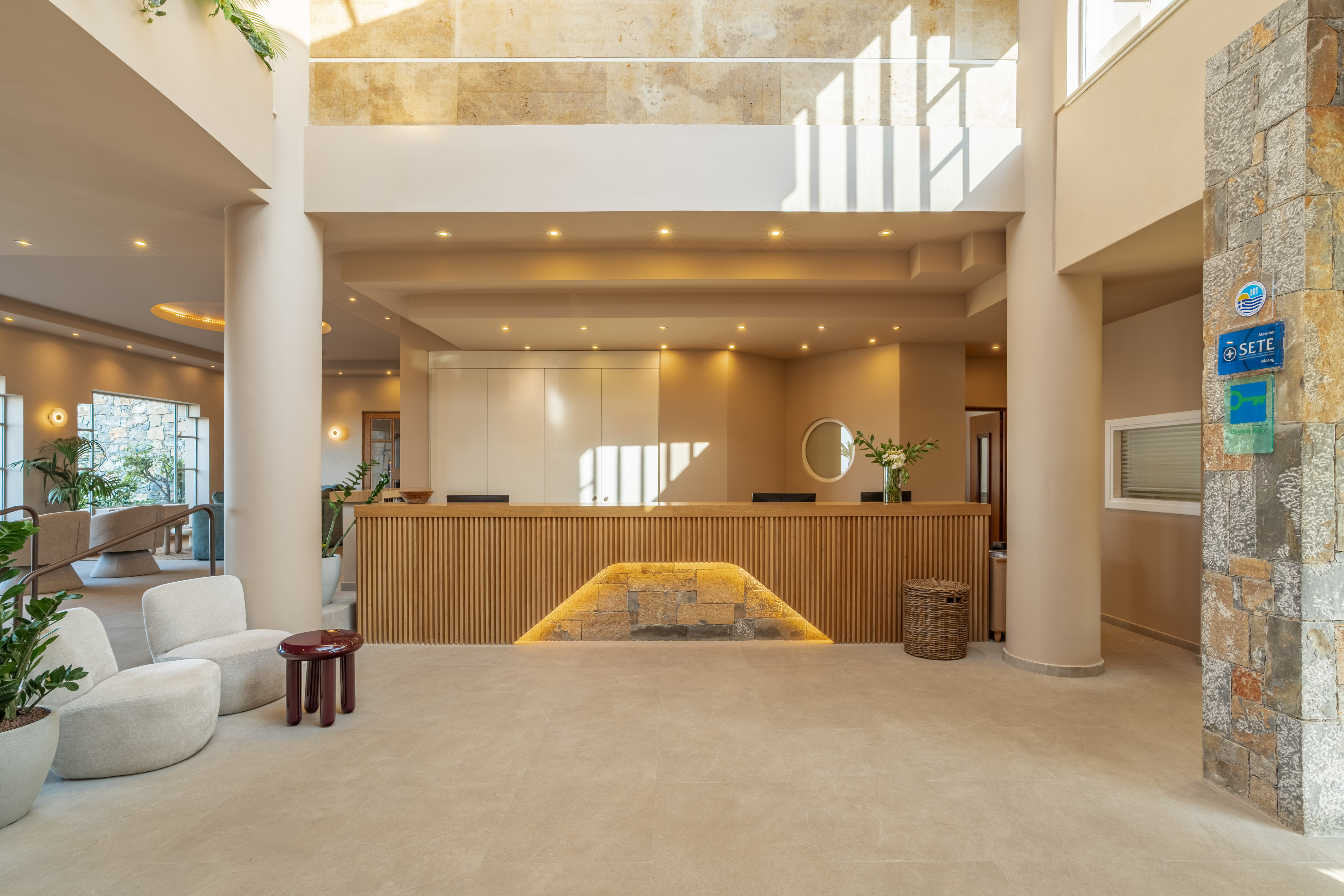 Modern hotel lobby with wood reception desk, natural light, and lounge seating.
