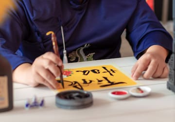 a person writing on a yellow paper