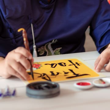 a person writing on a yellow paper