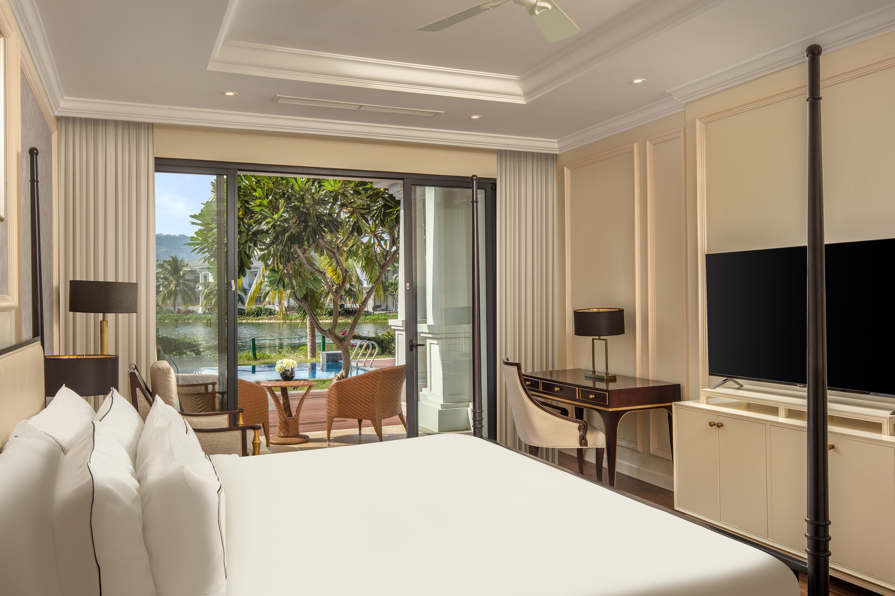 Luxury resort bedroom with balcony, tropical water view, and comfortable bed.