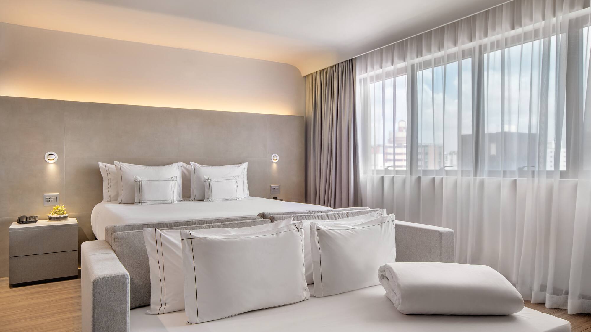 a bed with pillows and a bed in a room with curtains