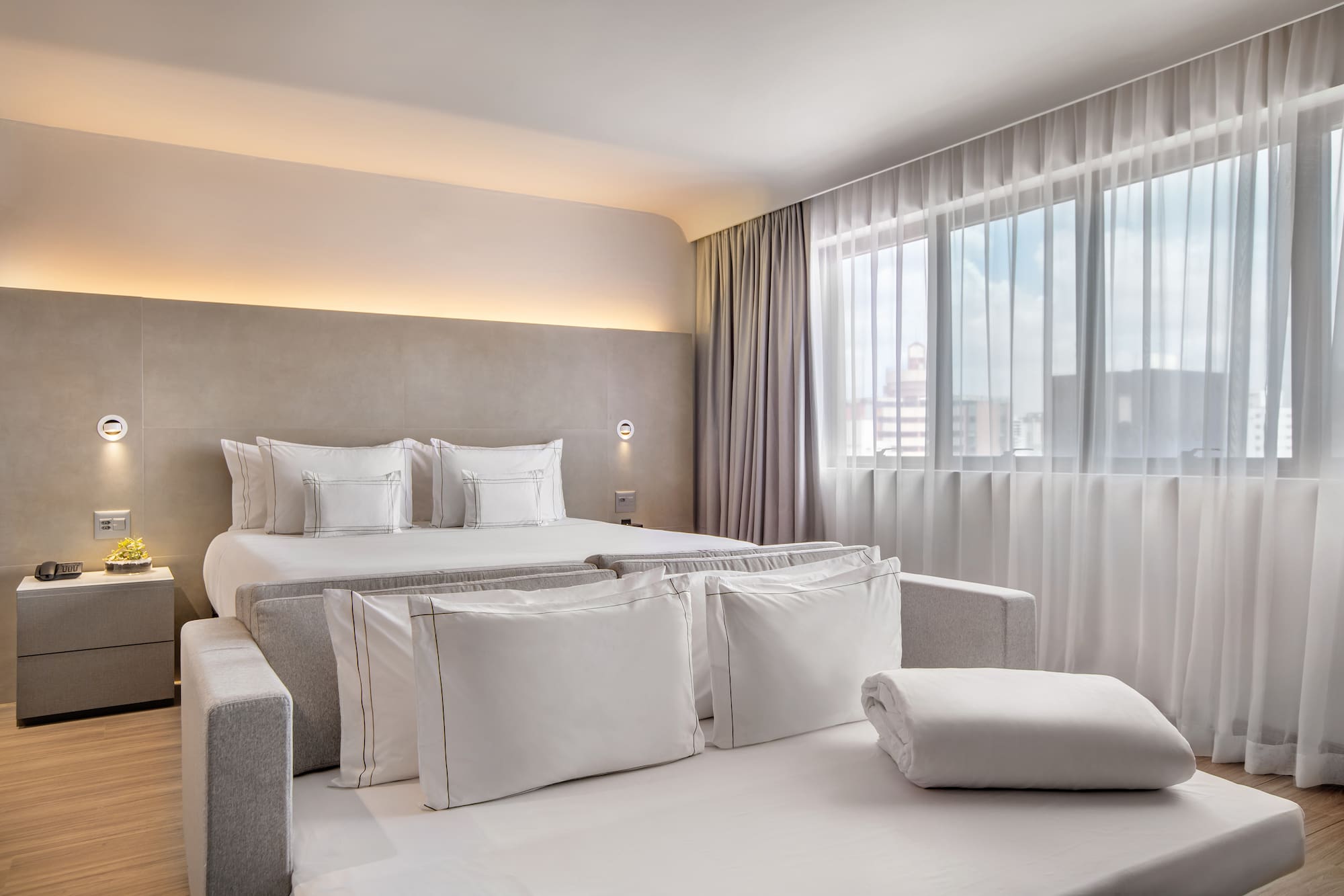 a bed with pillows and a bed in a room with curtains