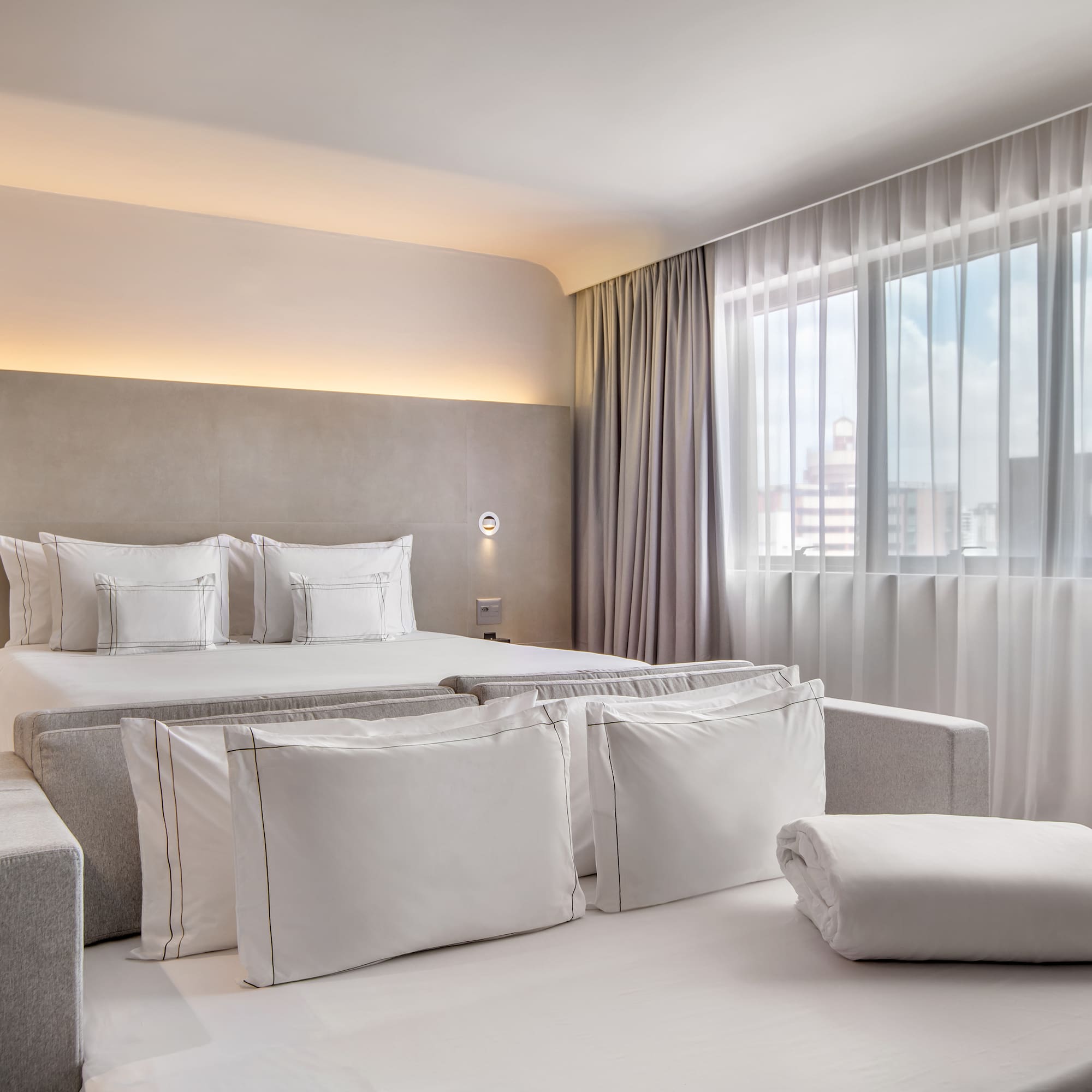 a bed with pillows and a bed in a room with curtains