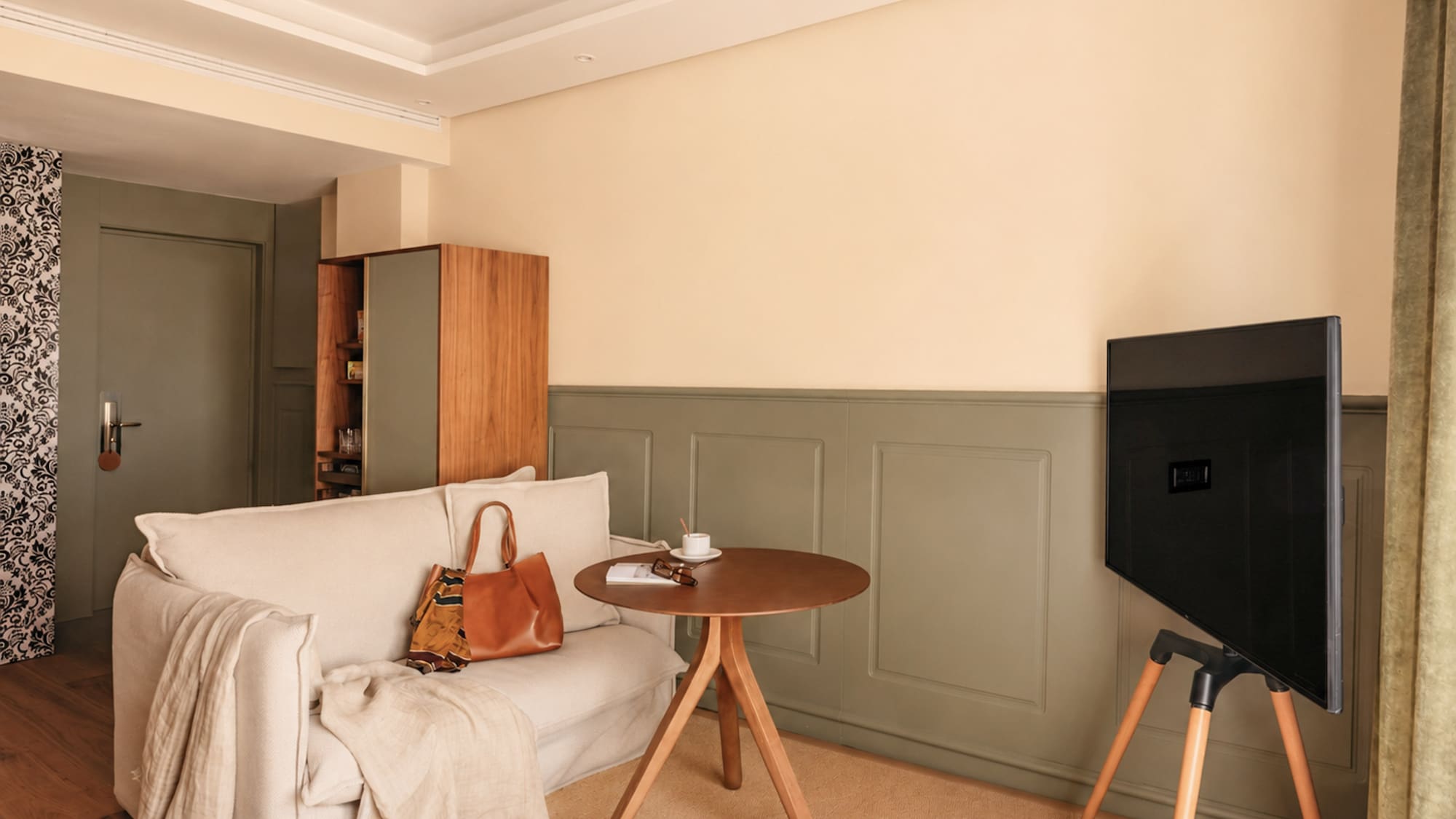 Neutral-toned living room with sofa, wooden side table, and tripod TV.