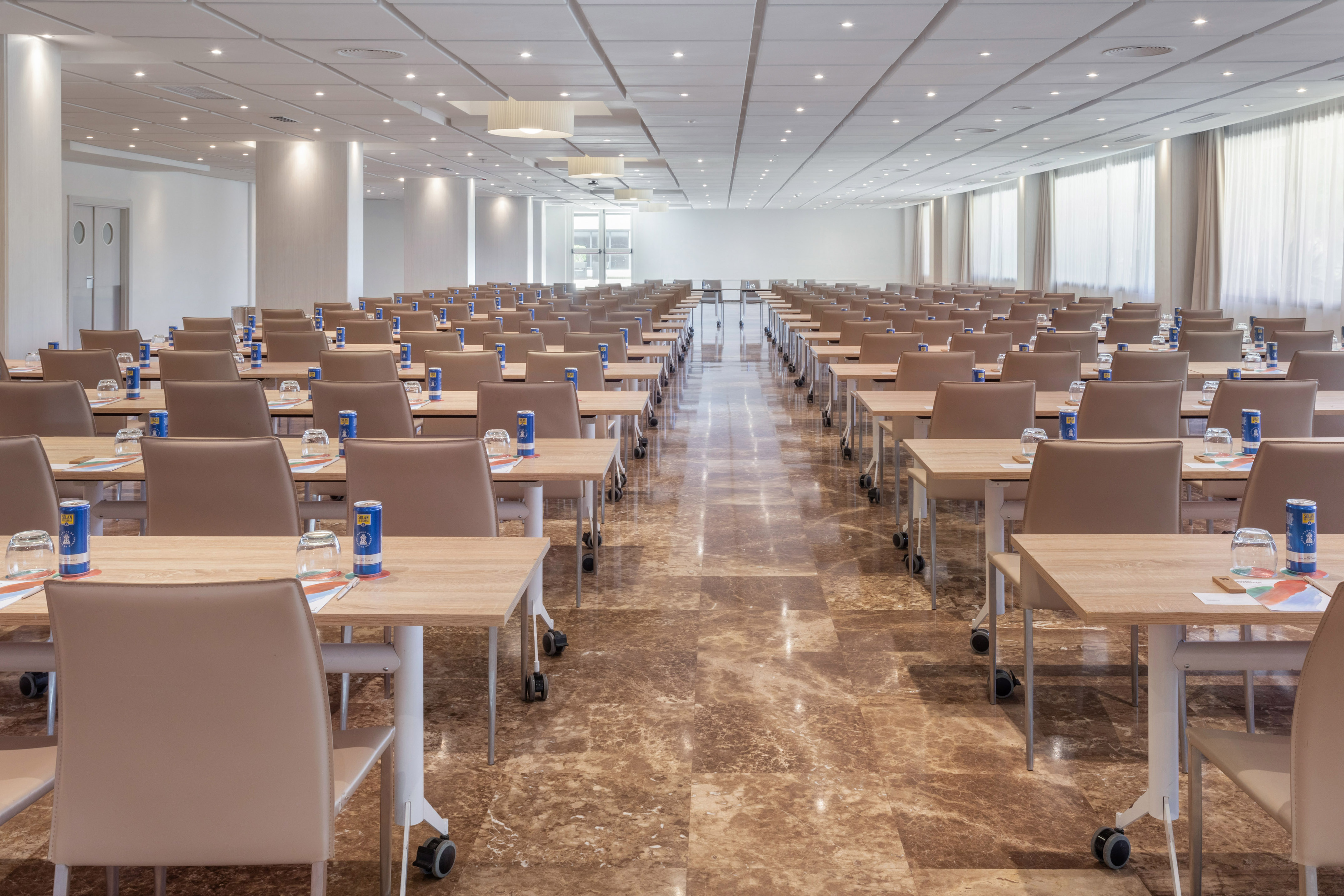 Modern conference room with rows of tables and chairs, set for a meeting.