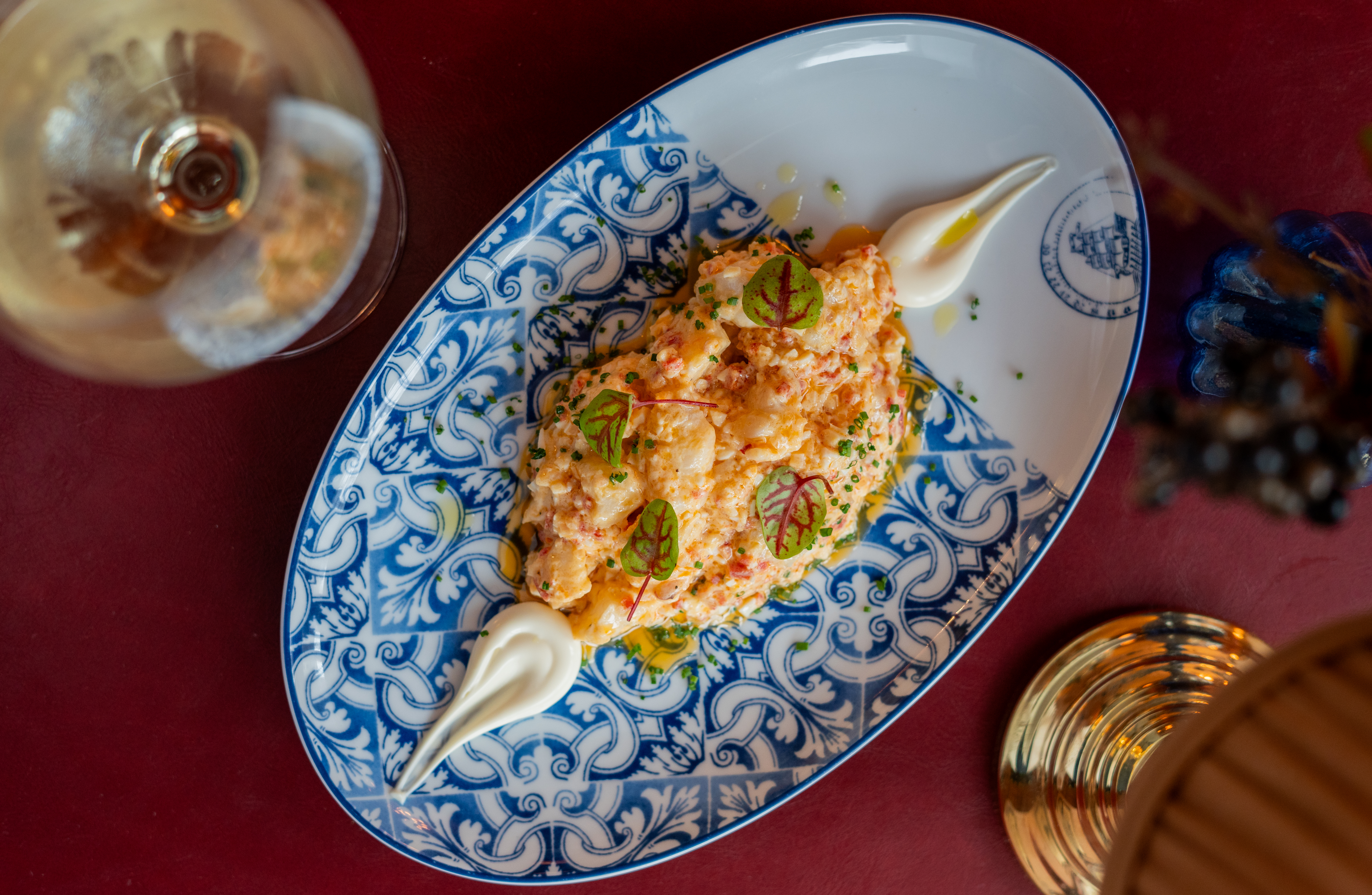 Creamy seafood salad with herbs and oil on blue patterned plate.