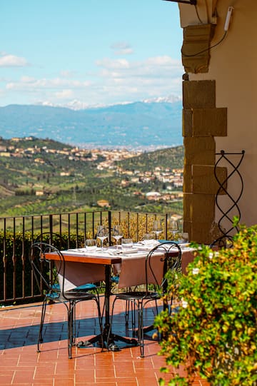 a table and chairs outside with a view of a valley in the background