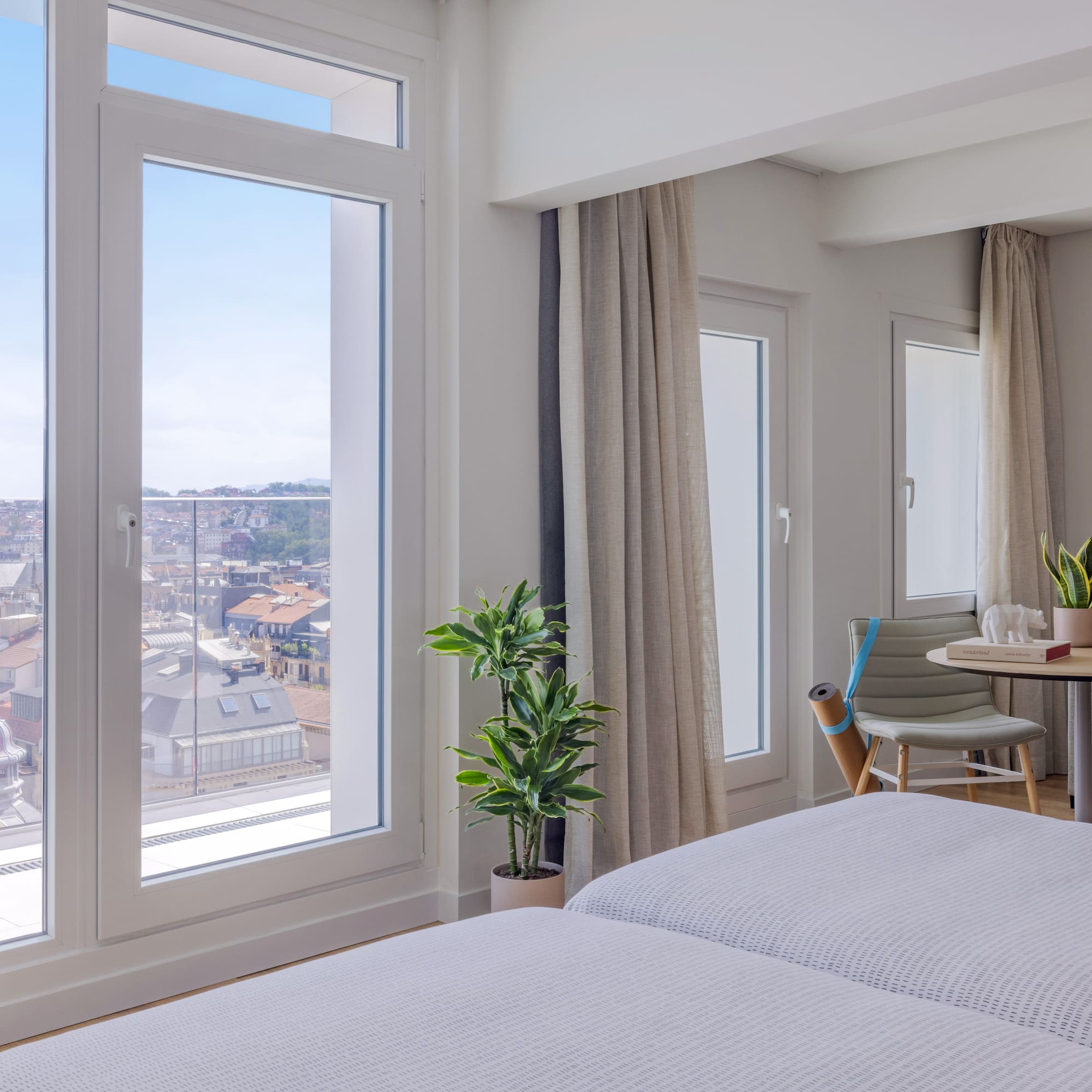 Habitación de hotel moderna con ventanales y vista urbana a la catedral.