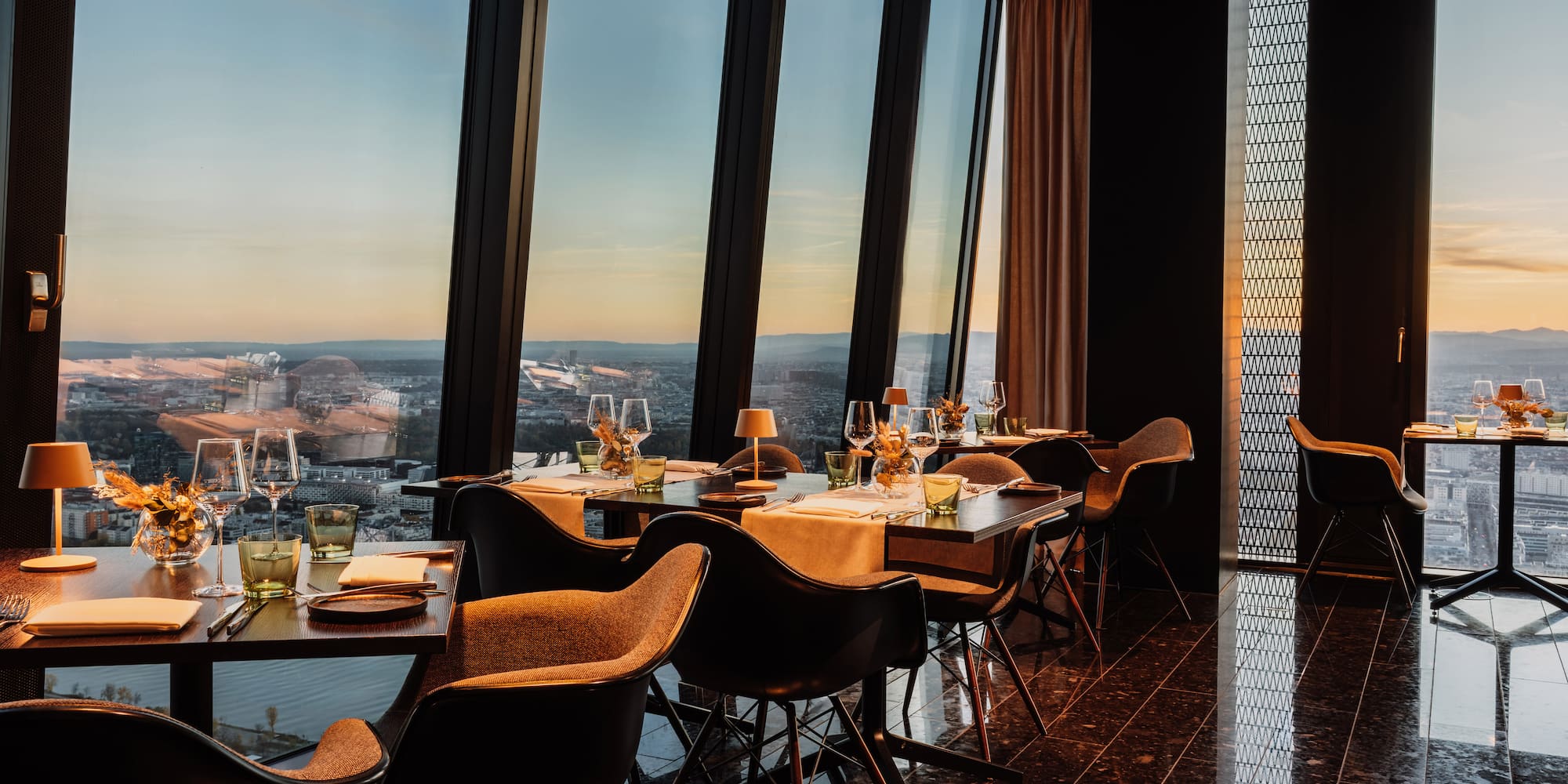 a table with wine glasses and a vase of flowers in front of a window