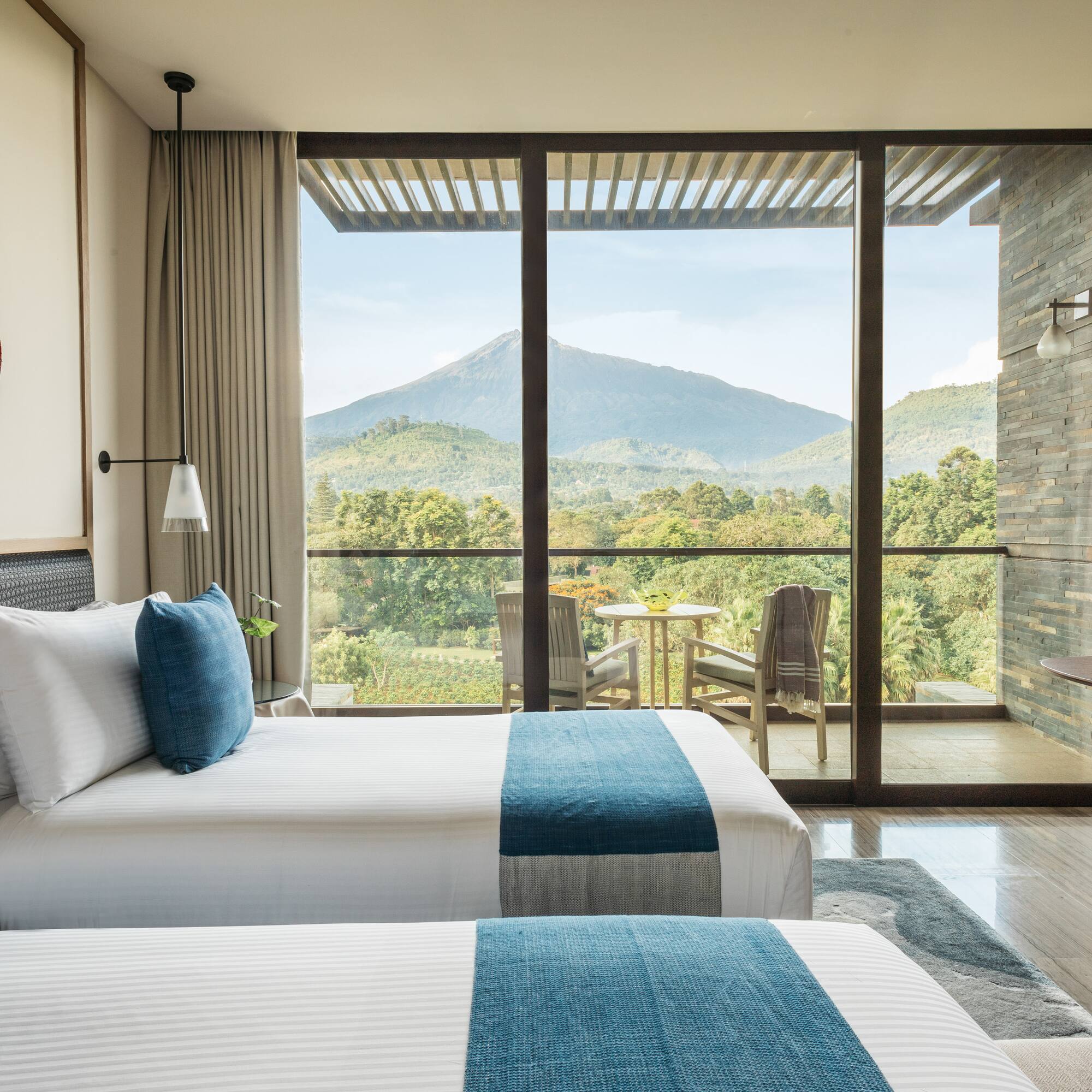 two beds in a room with a view of mountains and trees