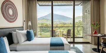 two beds in a room with a view of mountains and trees