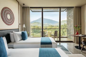 two beds in a room with a view of mountains and trees