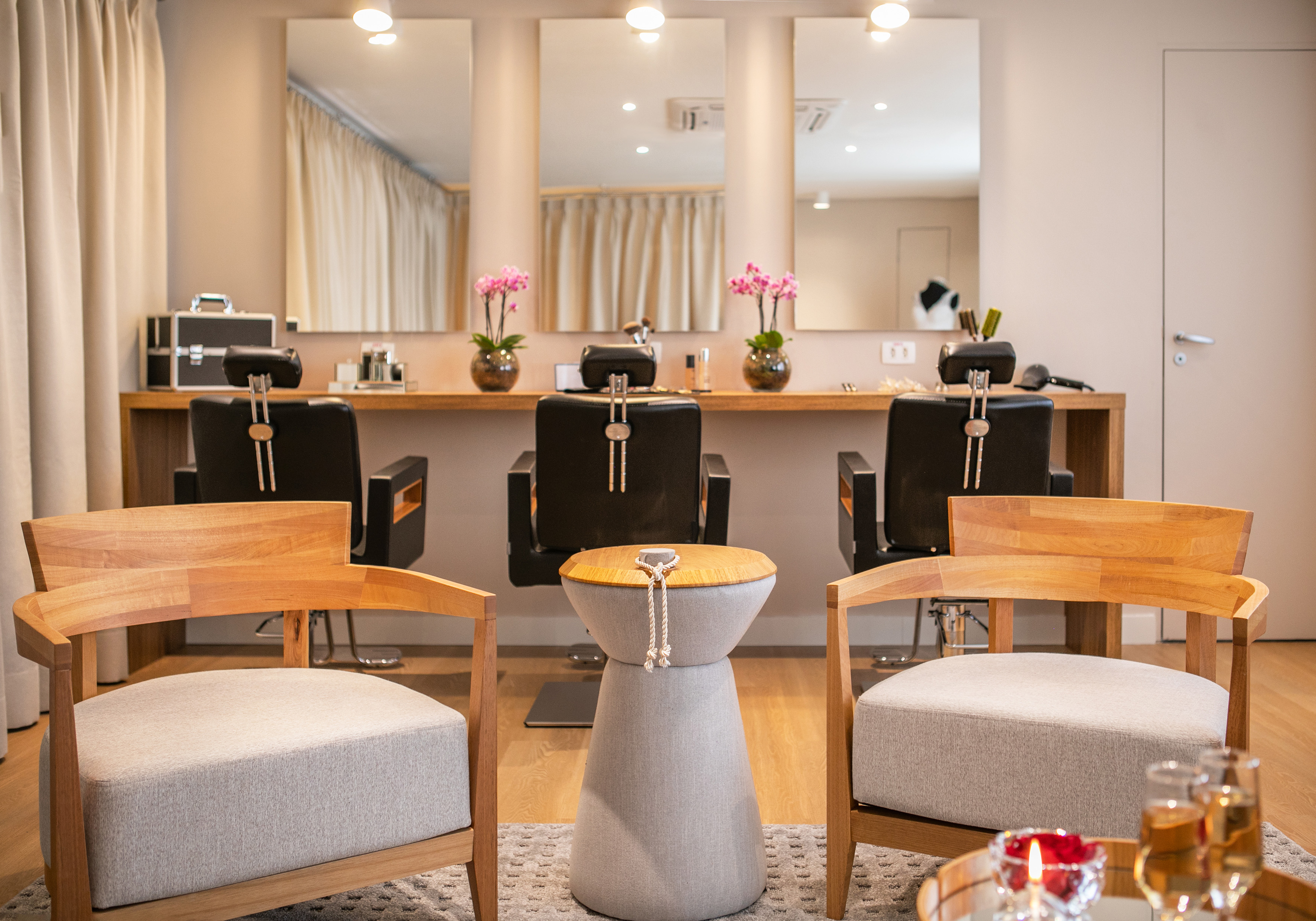 Modern beauty salon with three styling stations, mirrors, and waiting chairs.