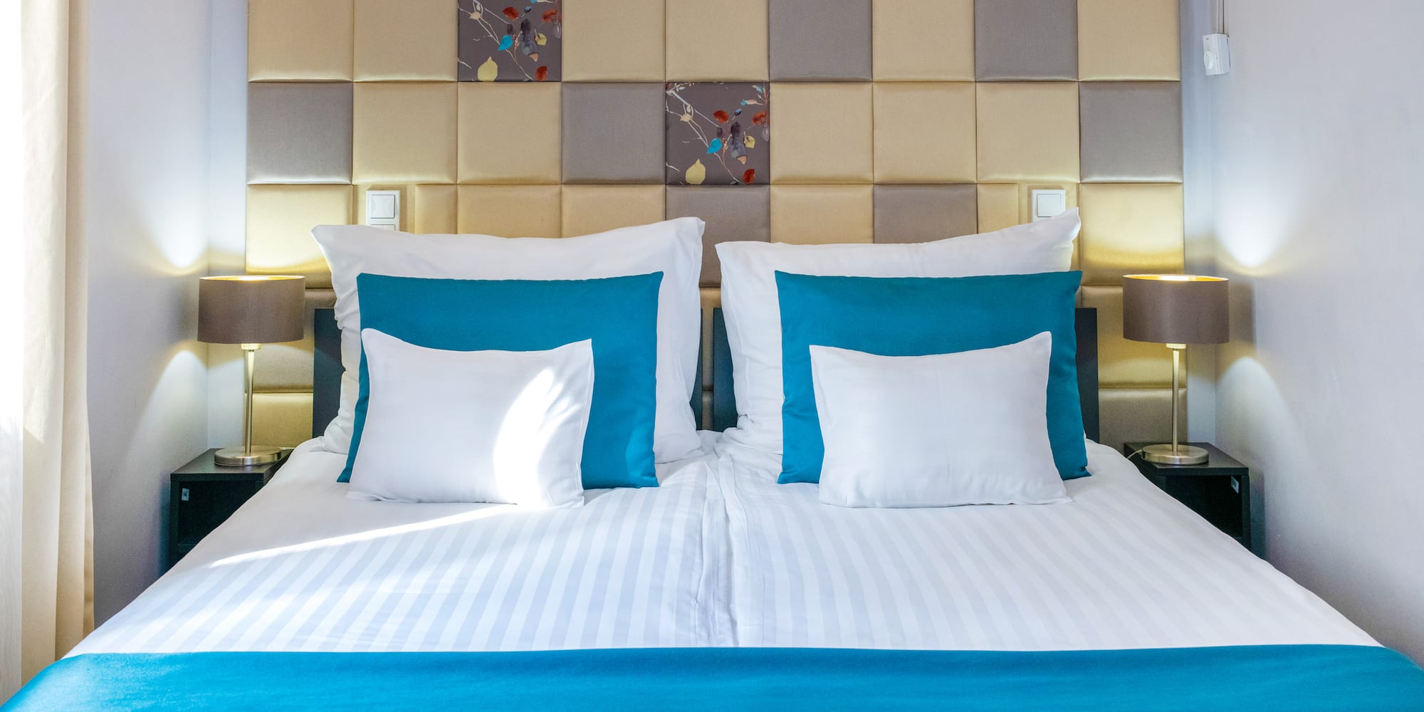 a bed with pillows and a lamp on the side