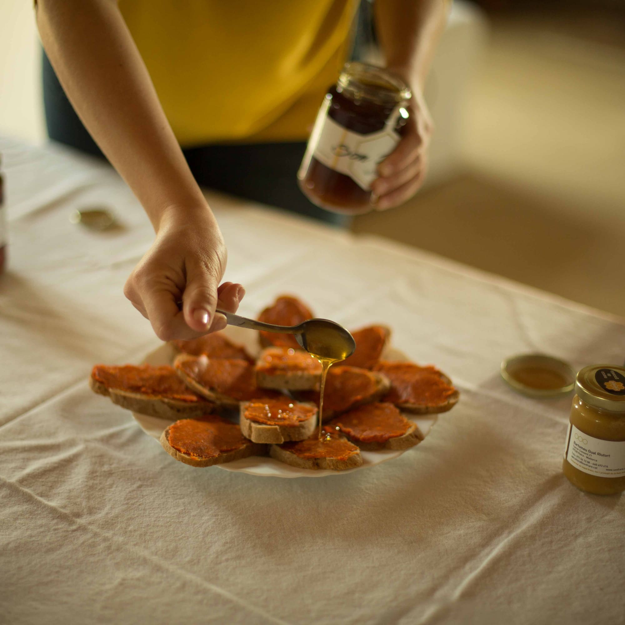 a person pouring honey on a plate of bread