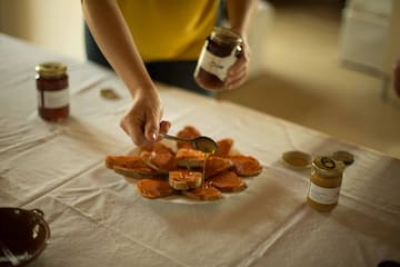 a person pouring honey on a plate of bread