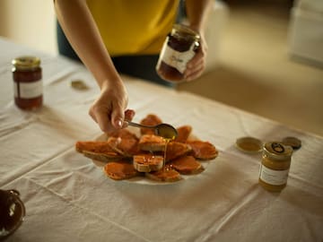 a person pouring honey on a plate of bread