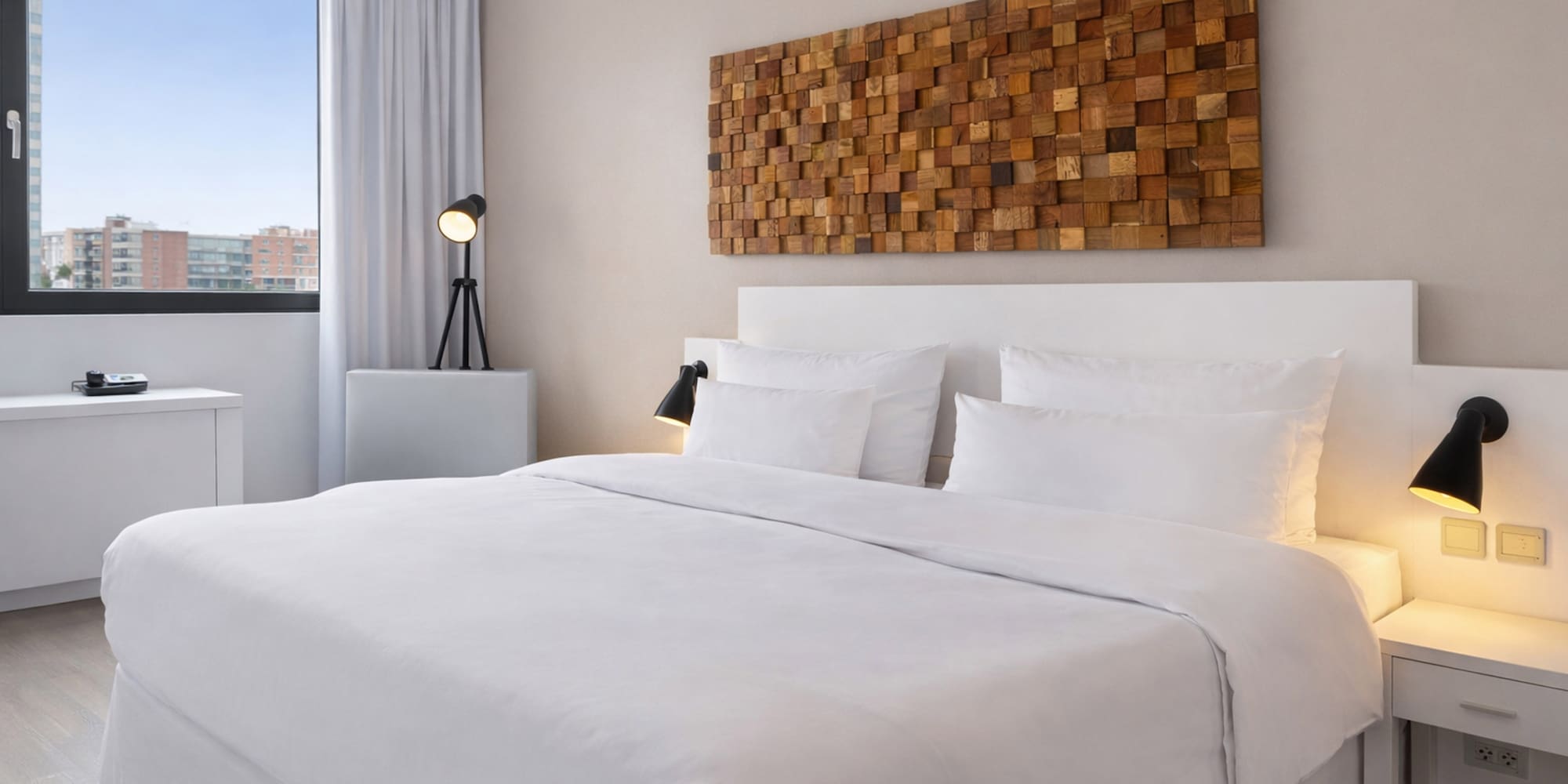 a bed with white sheets and pillows in a room with a lamp and a window